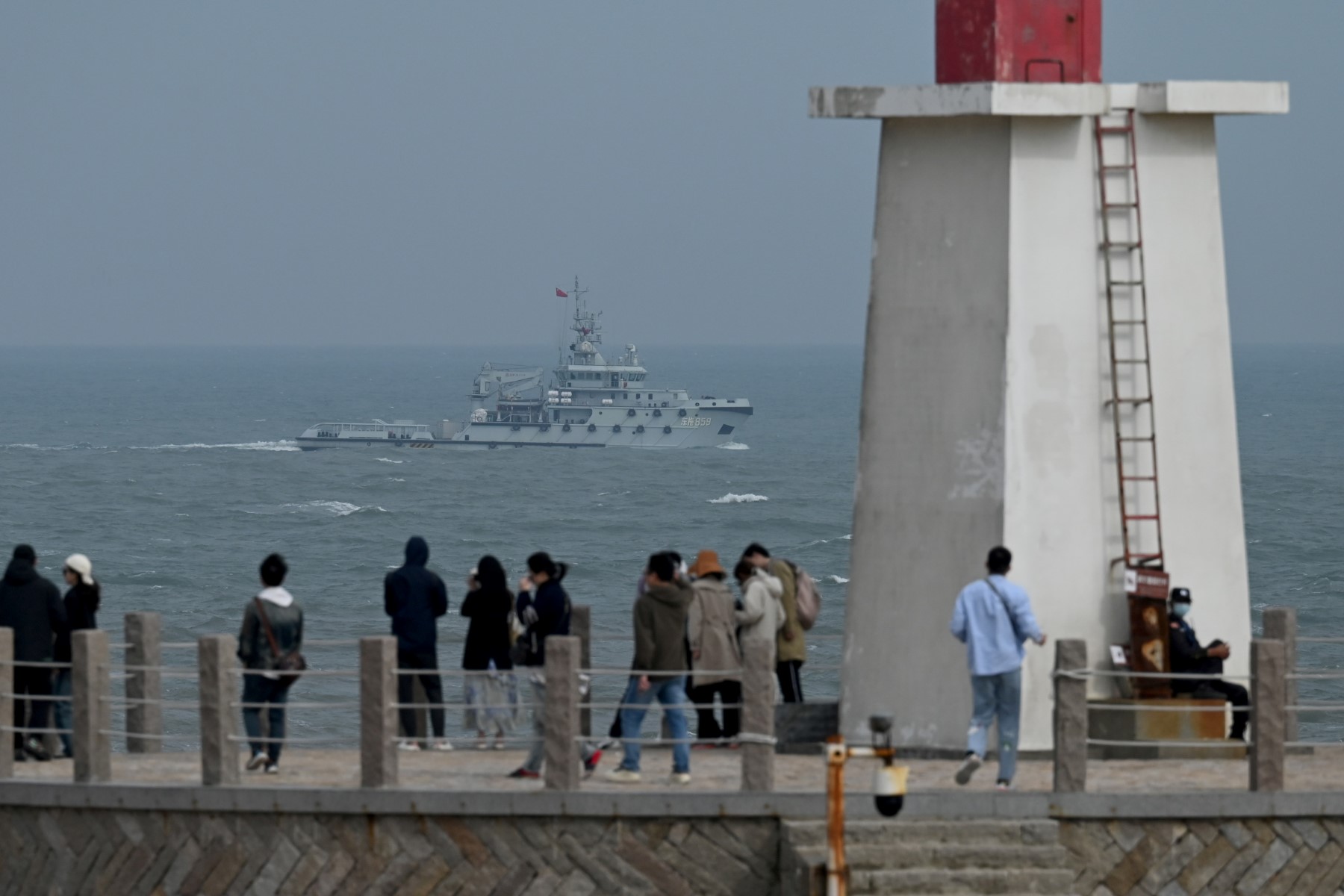 Un remorqueur de la marine de l'APL navigue dans le détroit de Taïwan, devant des touristes sur l'île de Pingtan, le point le plus proche de Taïwan, dans la province chinoise du Fujian (sud-est), le 7 avril 2023. (Photo de GREG BAKER / AFP)