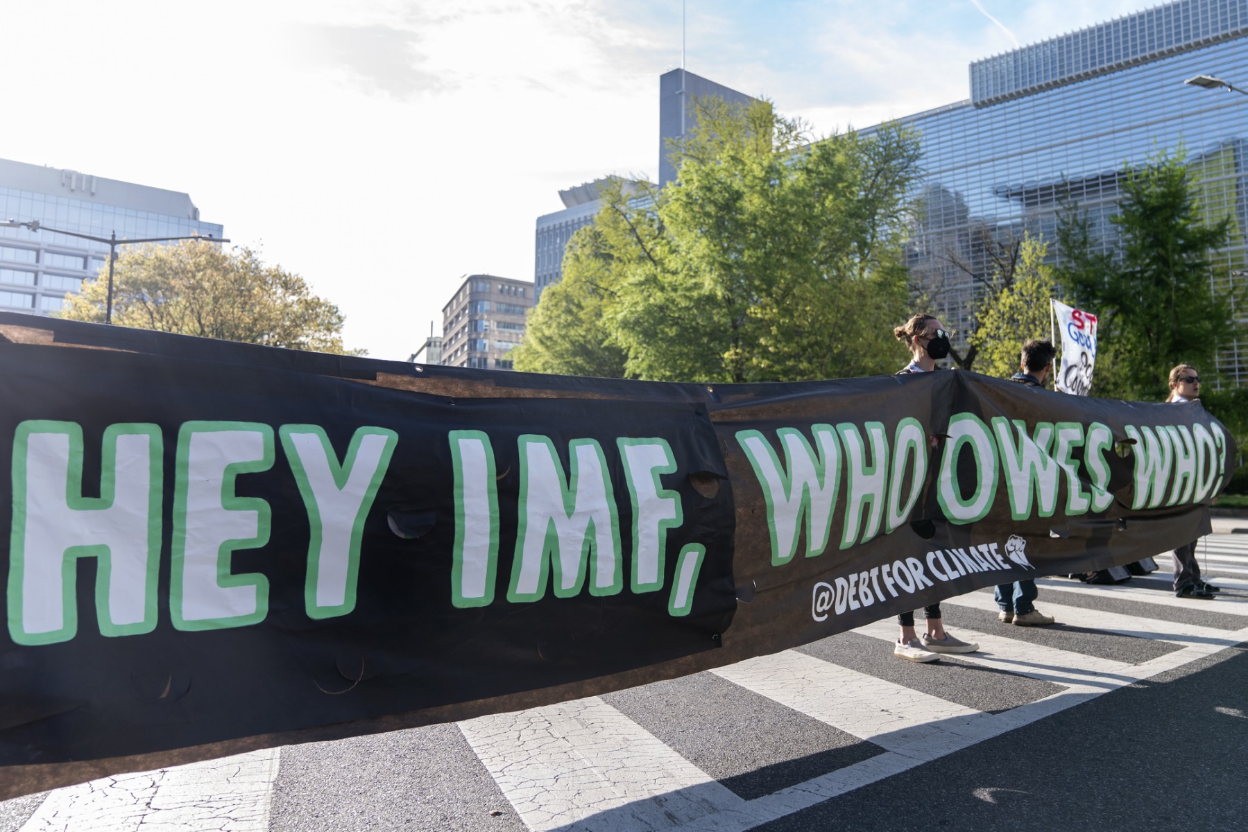 Des militants pour le climat bloquent la circulation devant le siège de la Banque mondiale (à l'arrière) pour demander à la Banque mondiale de cesser de financer les combustibles fossiles, lors des réunions de printemps du Groupe de la Banque mondiale et du Fonds monétaire international à Washington, DC, le 14 avril 2023. (Photo de Stefani Reynolds / AFP)