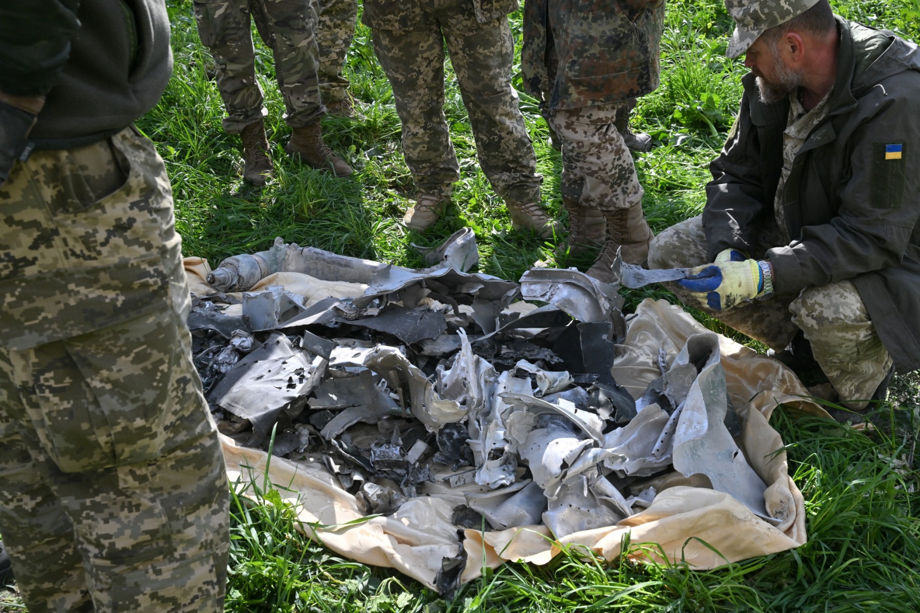 Des militaires ukrainiens examinent des débris dans un périmètre bouclé à Ouman, au sud de Kiev, le 28 avril 2023, après que des frappes de missiles russes ont visé plusieurs villes ukrainiennes pendant la nuit. (Photo de Sergei SUPINSKY / AFP)