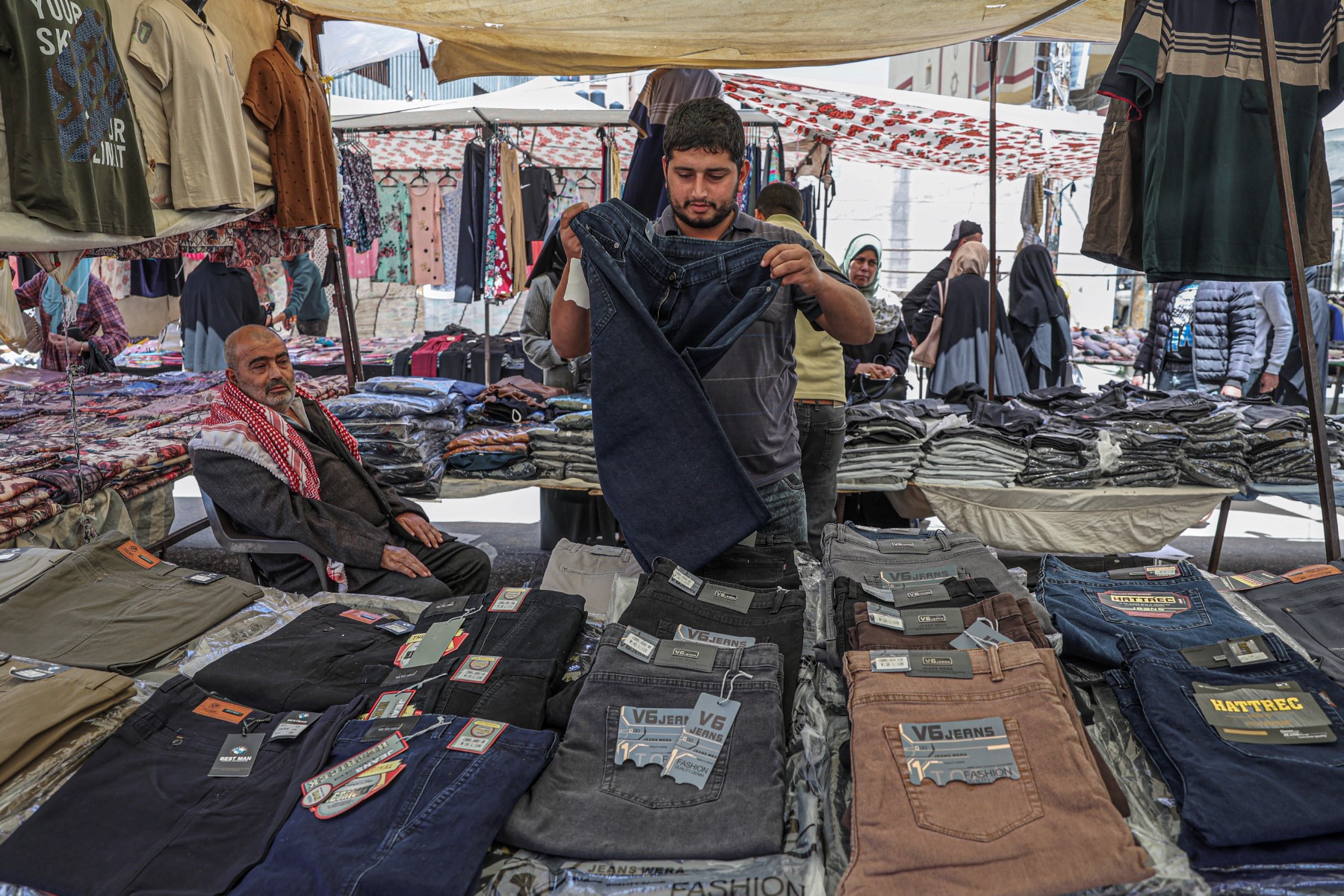 Une photo prise le 29 avril 2023 montre un vendeur palestinien présentant des vêtements sur un marché de la ville de Gaza. (Photo par SAID KHATIB / AFP)