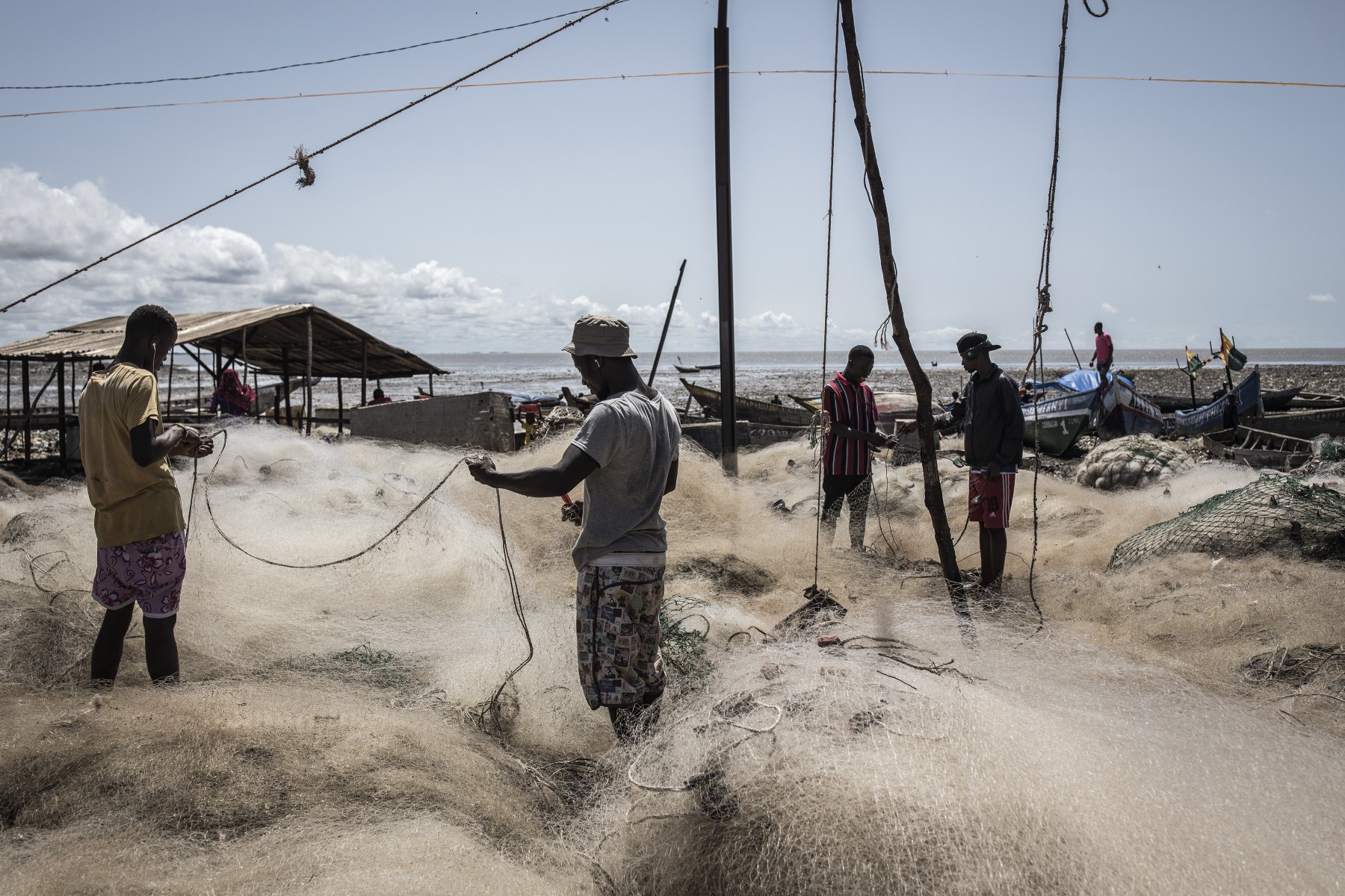 Des pêcheurs trient leurs filets de pêche en attendant la marée haute dans un village de pêche informel à Conakry, le 14 octobre 2020. (Photo/ John Wessels/AFP)