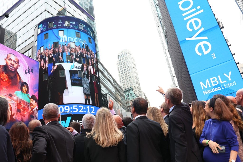 Des employés de Mobileye Global, Inc. et d'Intel regardent la sonnerie d'ouverture du Nasdaq sur un écran à Times Square le 26 octobre 2022 à New York. (Michael M. Santiago/Getty Images/AFP)