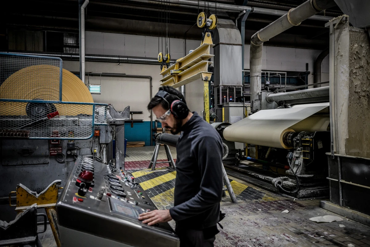 Un homme travaille sur la machine numéro 4 de l'usine "Papeterie du Leman" le 12 décembre 2022 à Publier, lors du processus de production du "papier bible", utilisé pour la production des livres de la collection Pléiade, de la maison d'édition Gallimard (Photo JEFF PACHOUD / AFP)