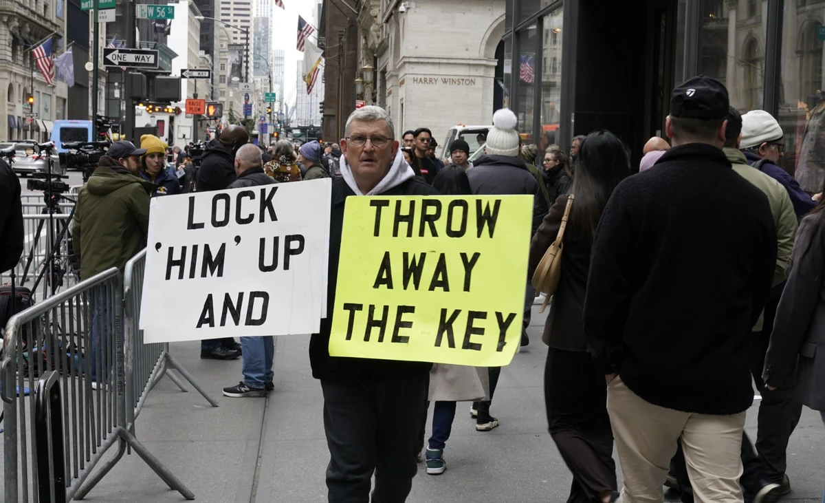 Un manifestant porte des pancartes devant la Trump Tower à New York le 31 mars 2023, au lendemain de l'inculpation de l'ancien président Donald Trump par un grand jury. (Photo par Timothy A. Clary / AFP)