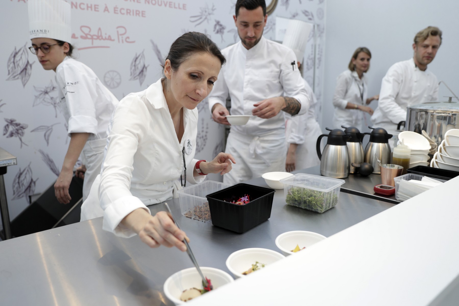 La chef française Anne-Sophie Pic (au centre) prépare des plats lors du festival Taste of Paris au Grand Palais à Paris, le 17 mai 2018. (Photo par Thomas SAMSON / AFP)