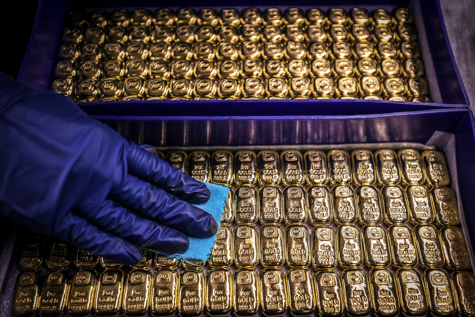 Un ouvrier polit des lingots d'or à la raffinerie ABC à Sydney le 5 août 2020. Le prix de l'or avait atteint 2 000 USD l'once sur les marchés pour la première fois la veille, dernière hausse en date d'une matière première considérée comme un refuge dans un contexte d'incertitude économique. (Photo DAVID GRAY / AFP)