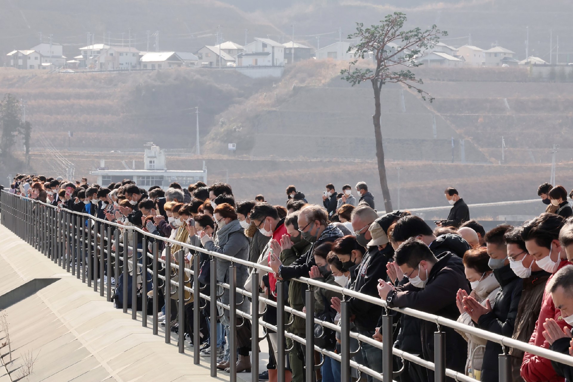 Des personnes participent à une prière silencieuse à côté du "pin miraculeux" pour se souvenir des victimes à l'occasion du 12e anniversaire du tremblement de terre, du tsunami et de la catastrophe nucléaire de 2011, à Rikuzentakata, dans la préfecture d'Iwate, le 11 mars 2023. (Photo par JIJI PRESS / AFP)
