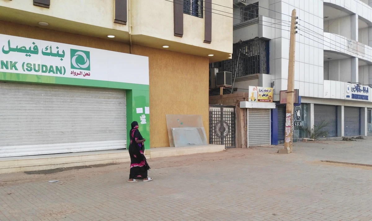 Une Soudanaise passe devant deux banques fermées dans une rue déserte de la capitale du Soudan, Khartoum, le 4 juin 2019. ( AFP / Ebrahim HAMID)