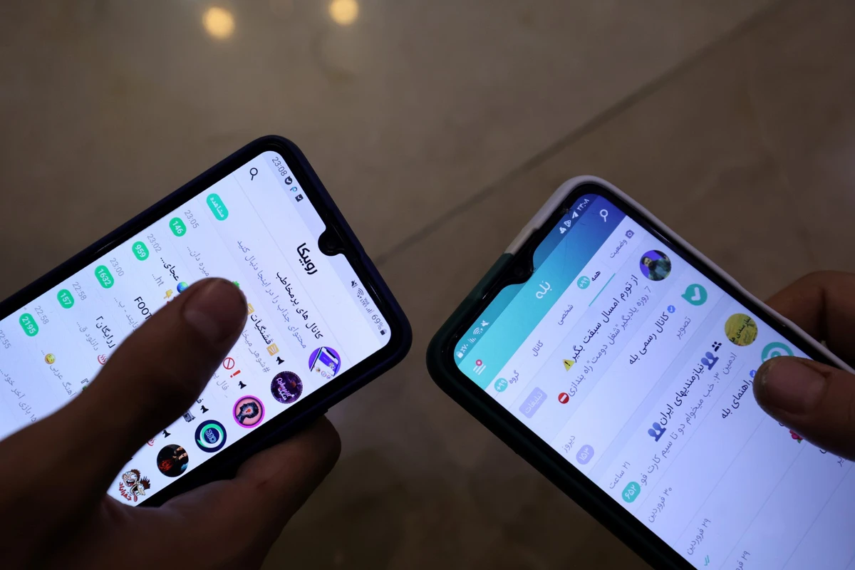 Sur cette photo prise le 19 avril 2023, des personnes montrent l'application de messagerie iranienne (Bale) sur leur téléphone portable à Téhéran. (Photo par ATTA KENARE / AFP)