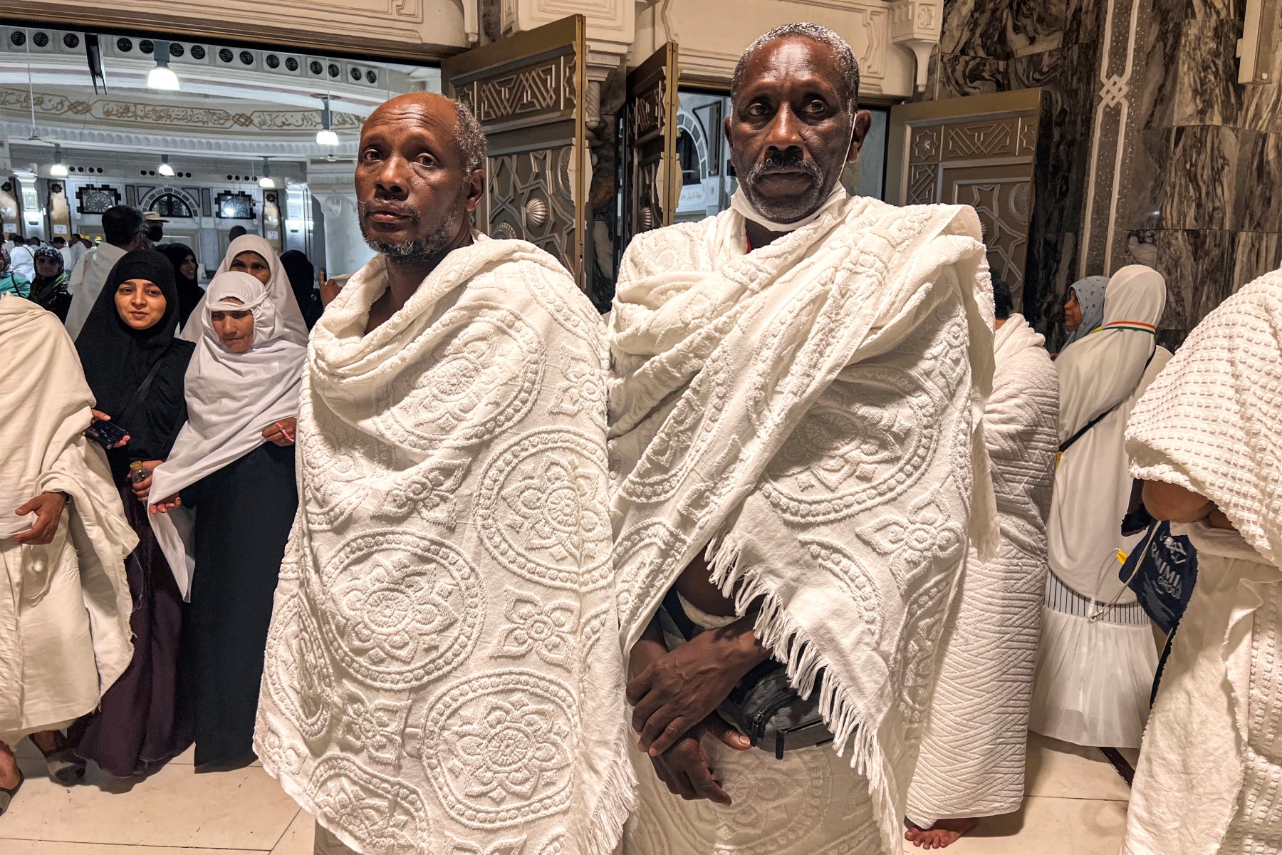 Les pèlerins soudanais Kamal Kabashi (à gauche), 52 ans, et Ahmed Jaber, 62 ans, se tiennent devant la Grande Mosquée, alors que les musulmans du monde entier arrivent pour le pèlerinage annuel du Hajj dans la ville sainte de La Mecque, le 22 juin 2023. (Photo de Sajjad HUSSAIN / AFP)