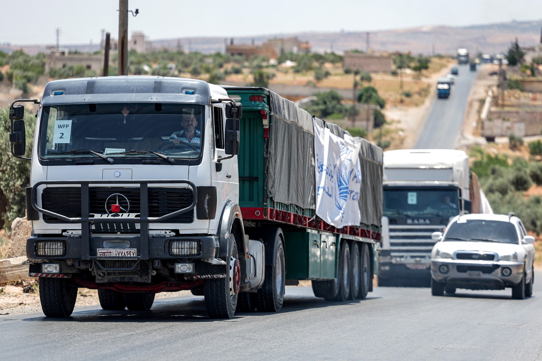 Des camions circulent dans un convoi d'aide des Nations Unies en route vers la ville d'Idlib, au nord-ouest de la Syrie, tenue par les rebelles, le 23 juin 2023. (Photo OMAR HAJ KADOUR / AFP)