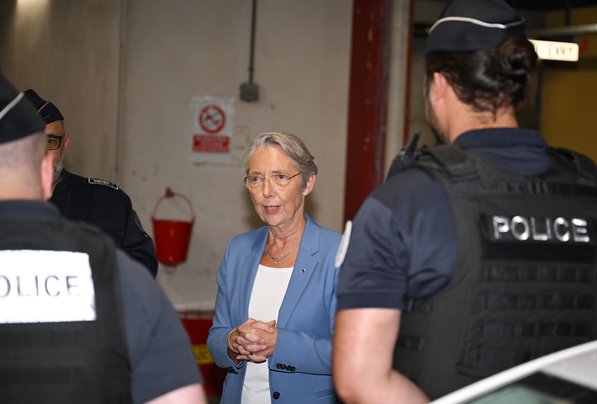 La Première ministre françaisz Elisabeth Borne (au centre) s'entretient avec des policiers devant le commissariat d'Evry-Courcouronnes, au sud de Paris, le 30 juin 2023, à la suite des émeutes qui ont éclaté trois jours après qu'un jeune homme de 17 ans a été abattu d'une balle dans la poitrine par la police à bout portant à Nanterre, dans la banlieue ouest de Paris. (Photo par Stefano RELLANDINI / POOL / AFP)
