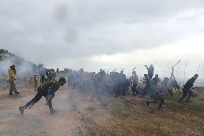 Des soldats libanais, des manifestants et des journalistes se baissent après que les troupes israéliennes ont tiré des gaz lacrymogènes dans le village frontalier sud-libanais de Kfar Chouba, le 9 juin 2023. (AP)