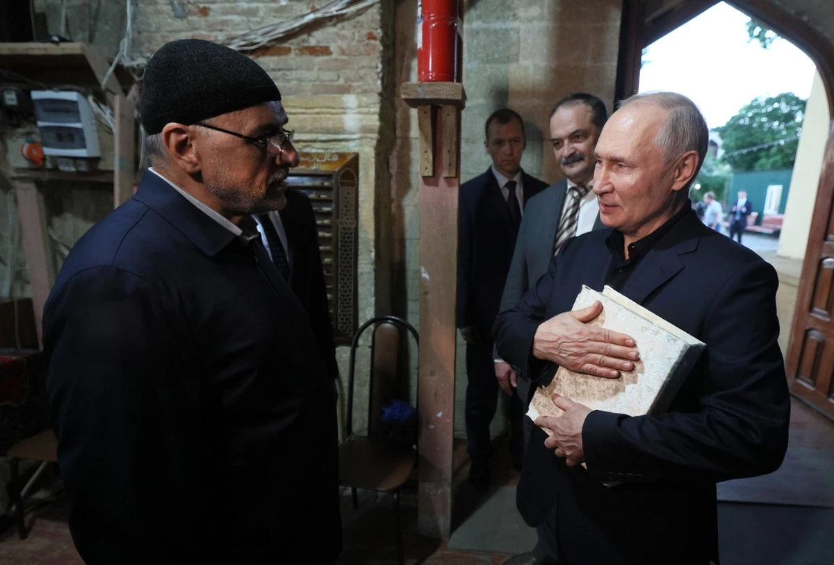 Le président russe Vladimir Poutine recevant un exemplaire du livre saint lors d’une visite la mosquée Juma à Derbent, dans la République russe du Daghestan, le 28 juin 2023. (Photo Gavriil Grigorov / SPUTNIK / AFP)