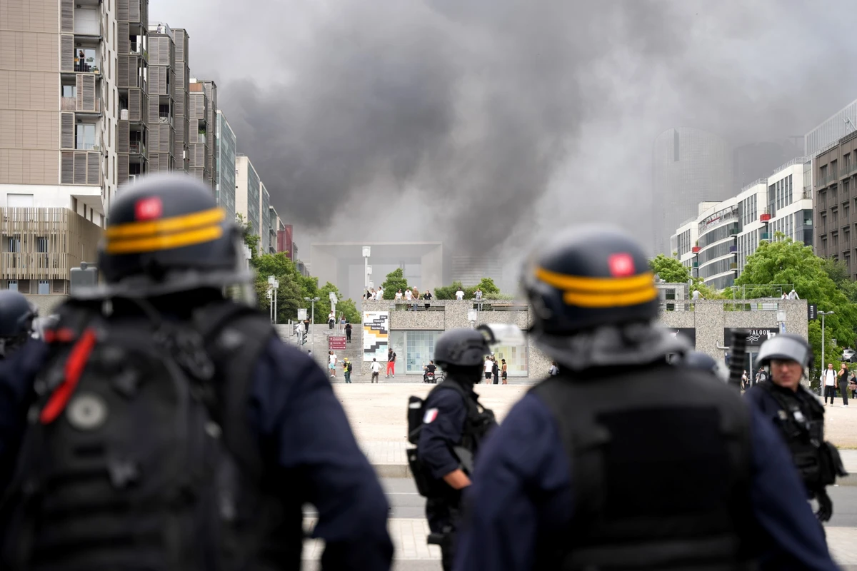 Des CRS font face à des manifestants, avec la Grande Arche de la Défense en arrière-plan, à la fin d'une marche commémorative pour un adolescent abattu par un policier, dans la banlieue parisienne de Nanterre, le 29 juin 2023. (Photo Zakaria ABDELKAFI / AFP)