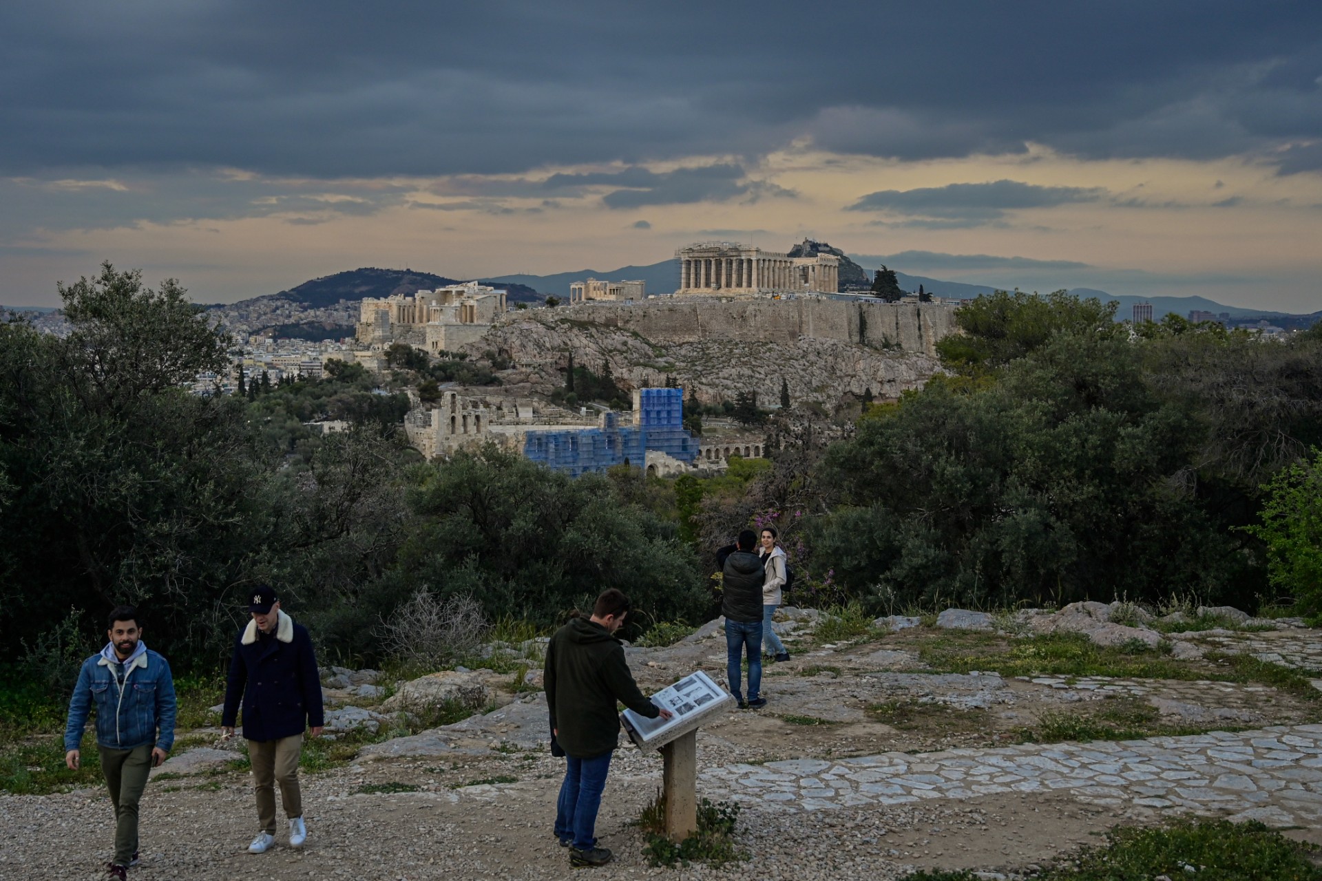 Des touristes apprécient la vue de l'ancienne Acropole depuis la colline de Filoppapou à Athènes, le 7 avril 2023. (Photo de Louisa GOULIAMAKI / AFP)