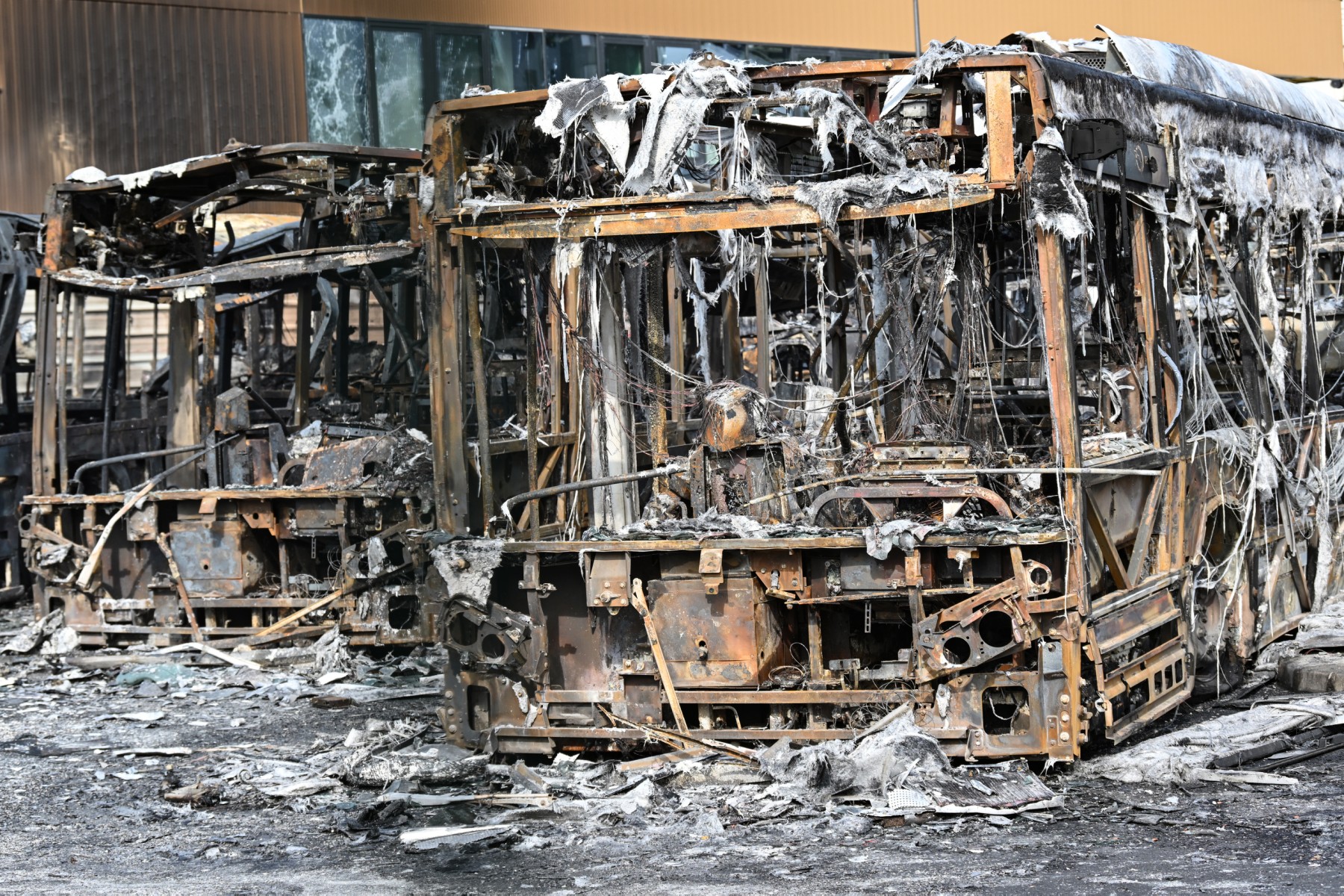 Cette photo prise le 30 juin 2023 montre des bus brûlés à travers les grilles de la gare routière du Fort d'Aubervilliers, en face du futur site olympique de natation de Paris 2024, à Aubervilliers, au nord de Paris. (Photo par Bertrand GUAY / AFP)