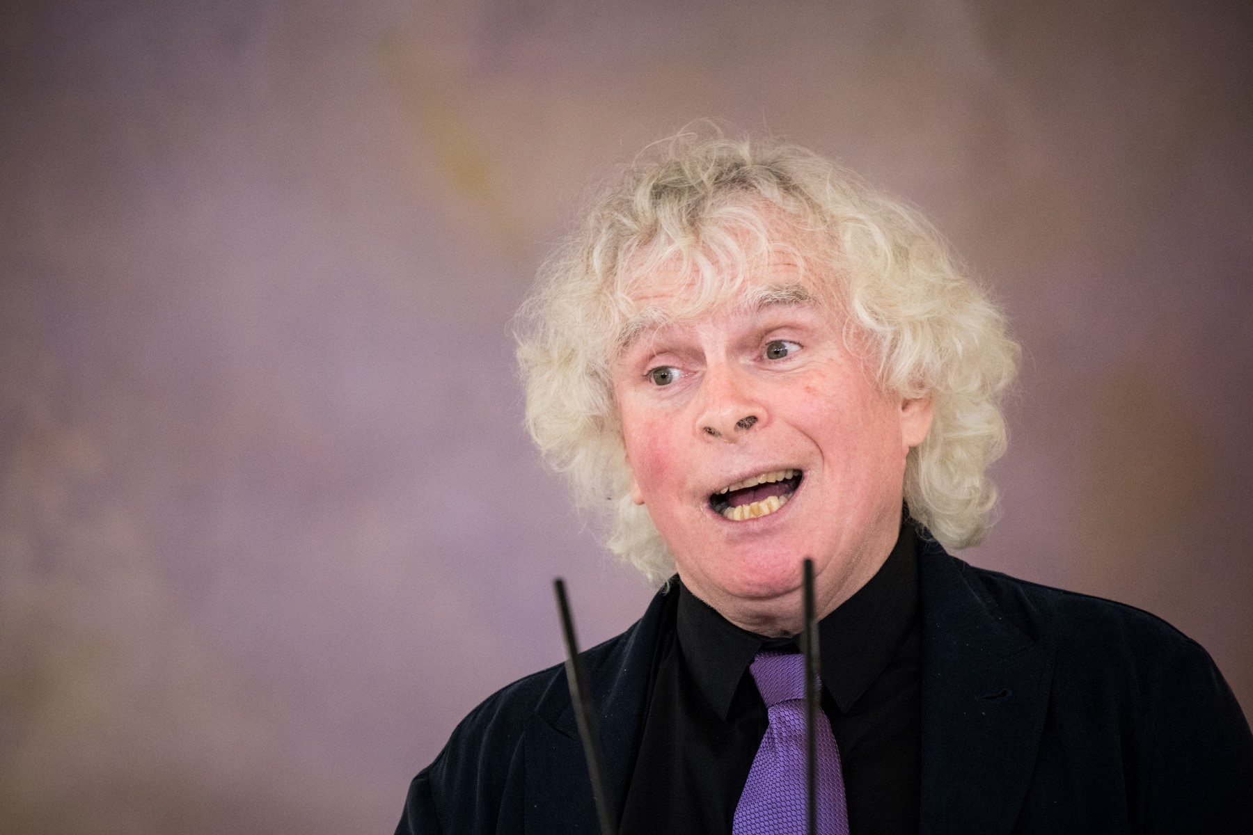 Le chef d'orchestre britannique Sir Simon Rattle prononce un discours après avoir reçu la Croix fédérale du mérite (Bundesverdienstkreuz) des mains du président allemand, le 8 février 2022 au château de Bellevue à Berlin. (Photo STEFANIE LOOS / AFP
