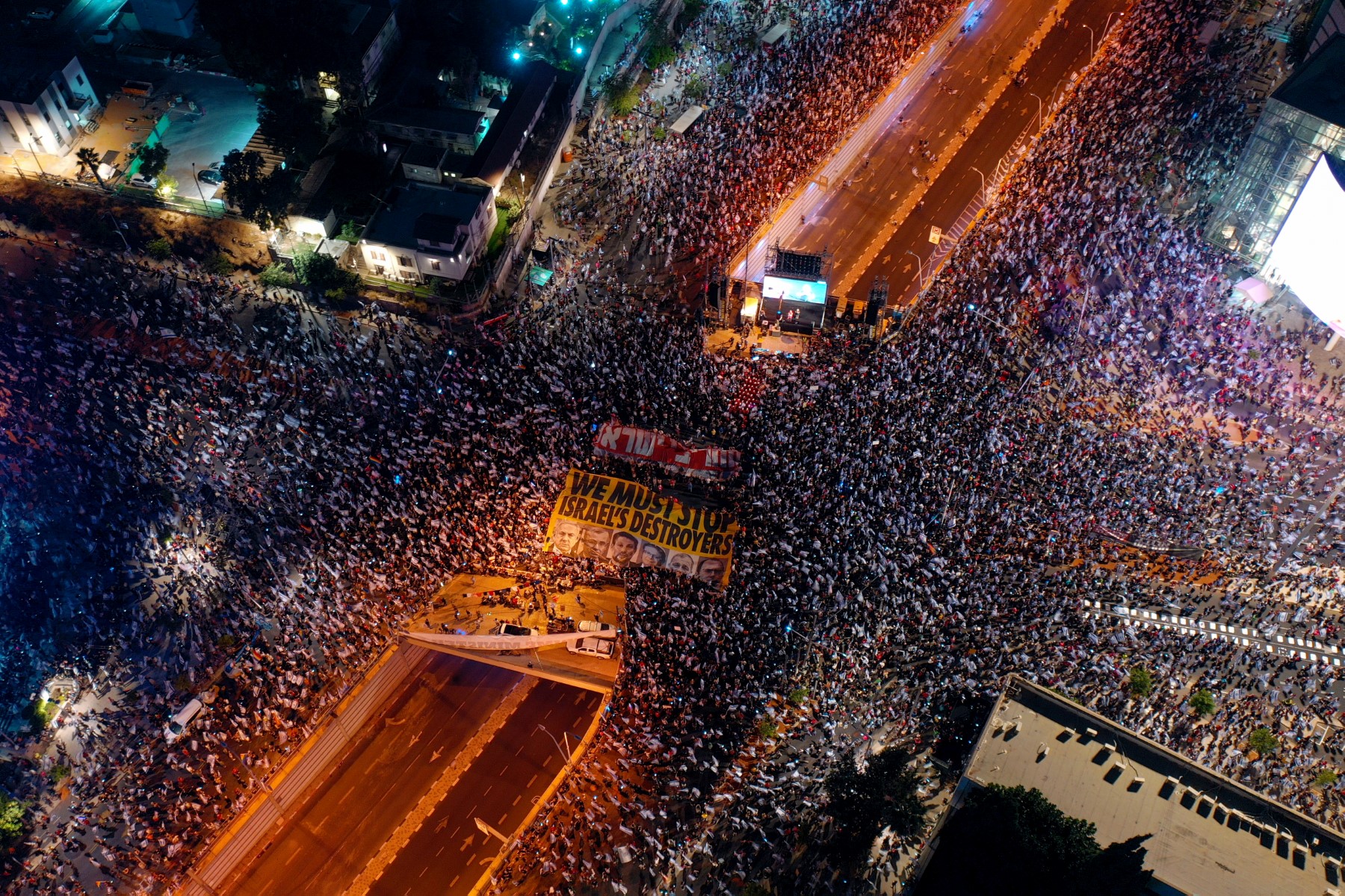 Une photo aérienne montre des manifestants israéliens brandissant des banderoles et des drapeaux lors d'un rassemblement à Tel Aviv pour protester contre le plan de réforme judiciaire du gouvernement israélien, le 1er juillet 2023. (Photo par Gil COHEN-MAGEN / AFP)
