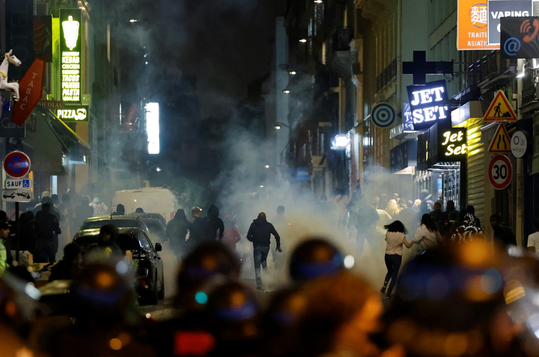 Des manifestants courent alors que des policiers français utilisent des gaz lacrymogènes à Paris le 2 juillet 2023, cinq jours après qu'un jeune homme de 17 ans a été tué par la police à Nanterre, dans la banlieue ouest de Paris. (Photo Ludovic MARIN / AFP)