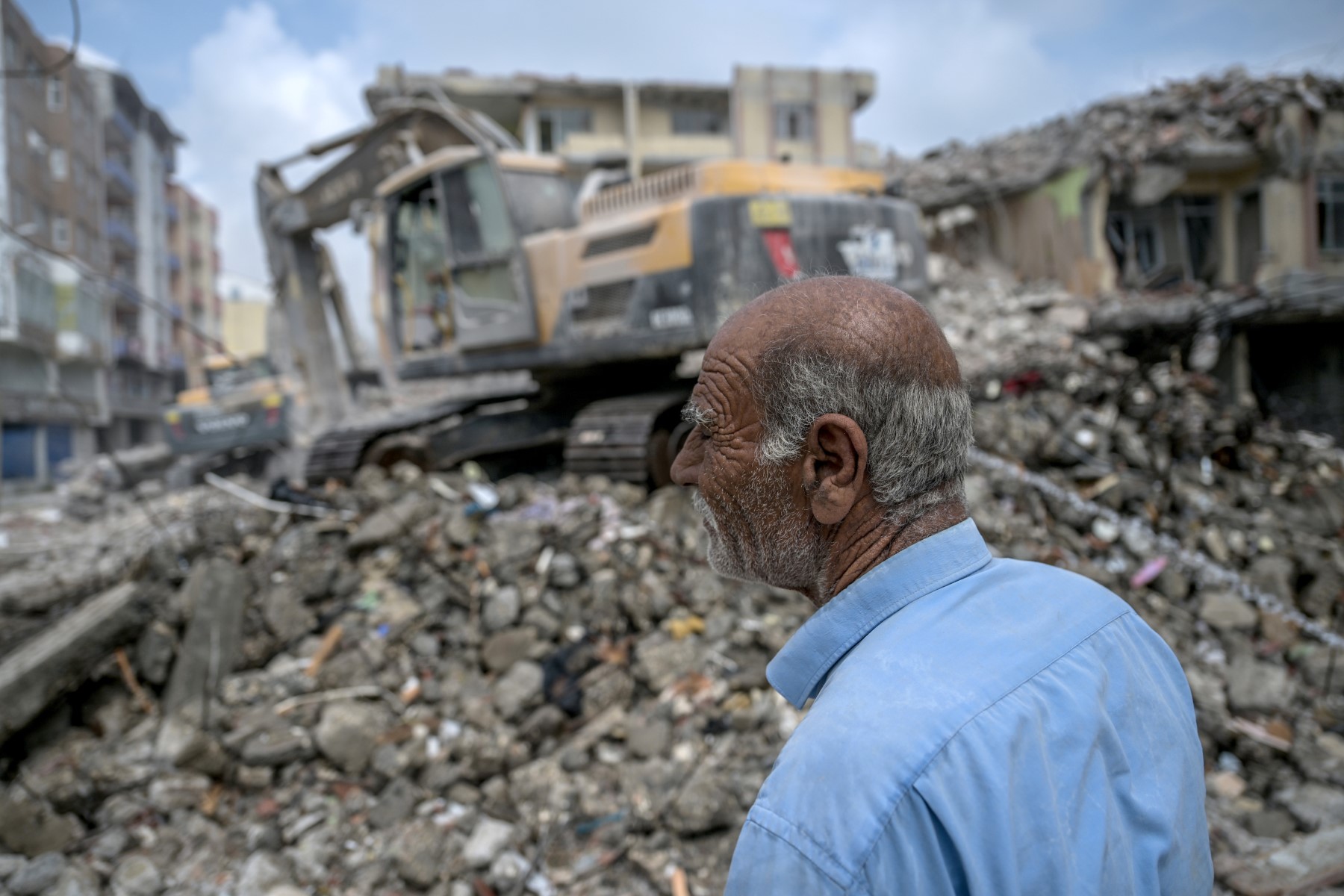 Le 9 juillet 2023, à Samandag, un homme observe des pelleteuses qui nettoient les décombres des bâtiments effondrés, cinq mois après une secousse de magnitude 7,8 et ses répliques qui ont ravagé des pans entiers de la région montagneuse du sud-est de la Turquie. (Photo OZAN KOSE / AFP)