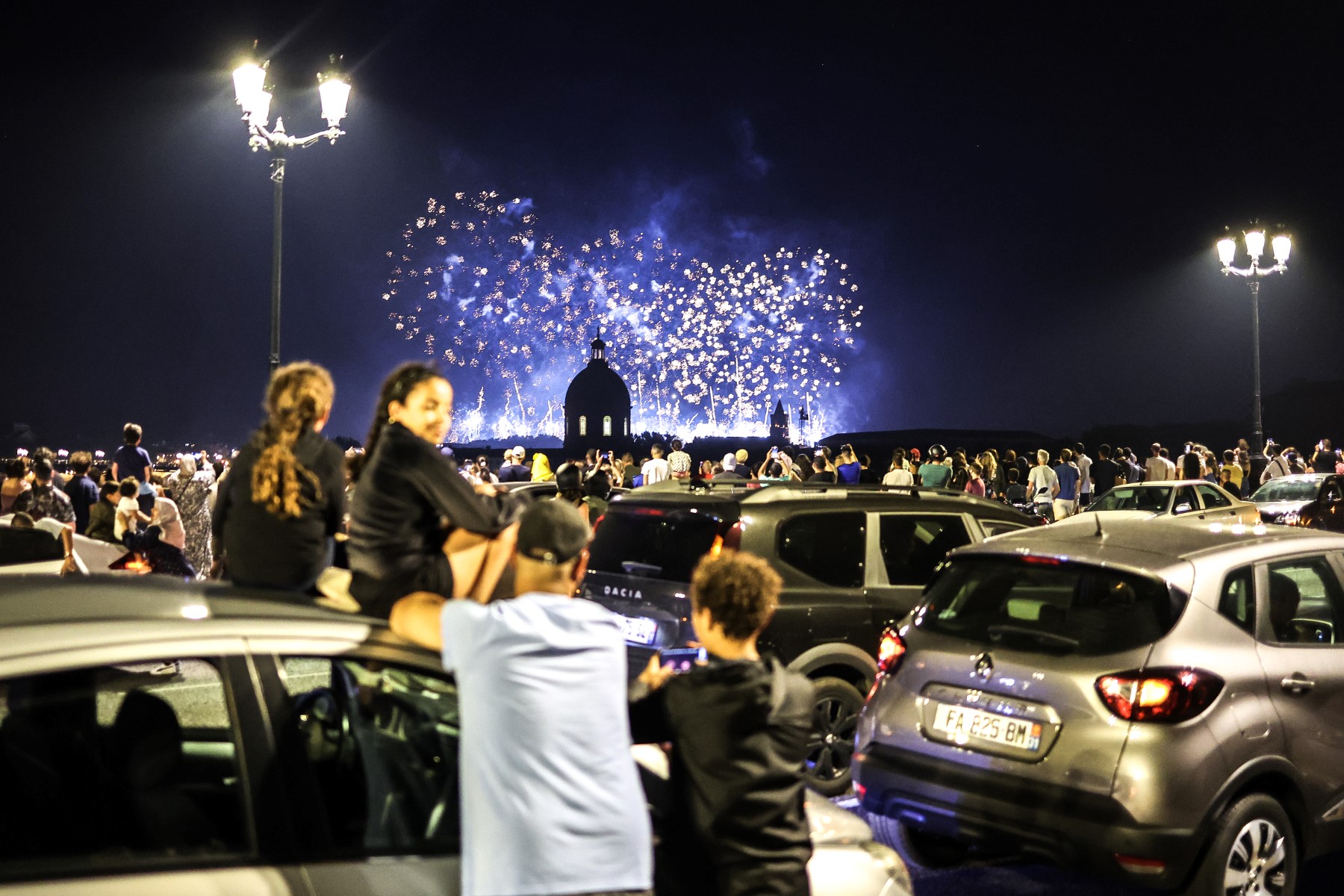 Des personnes regardent les feux d'artifice exploser au-dessus du Dôme de La Grave dans le cadre des célébrations annuelles du Jour de la Bastille à Toulouse, dans le sud-ouest de la France, le 14 juillet 2023. (Photo par CHARLY TRIBALLEAU / AFP)