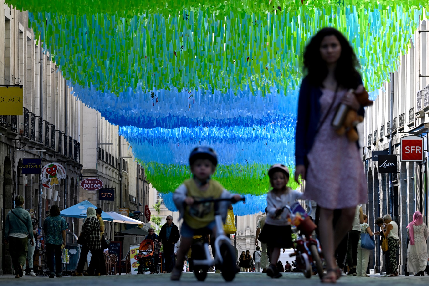 Des piétons marchent sous un dispositif d'ombrage pour lutter contre la chaleur excessive dans une rue commerçante du centre-ville de Rennes, dans l'ouest de la France, le 20 juillet 2023, alors que l'Europe est frappée par une importante vague de chaleur. (Photo par Damien MEYER / AFP)