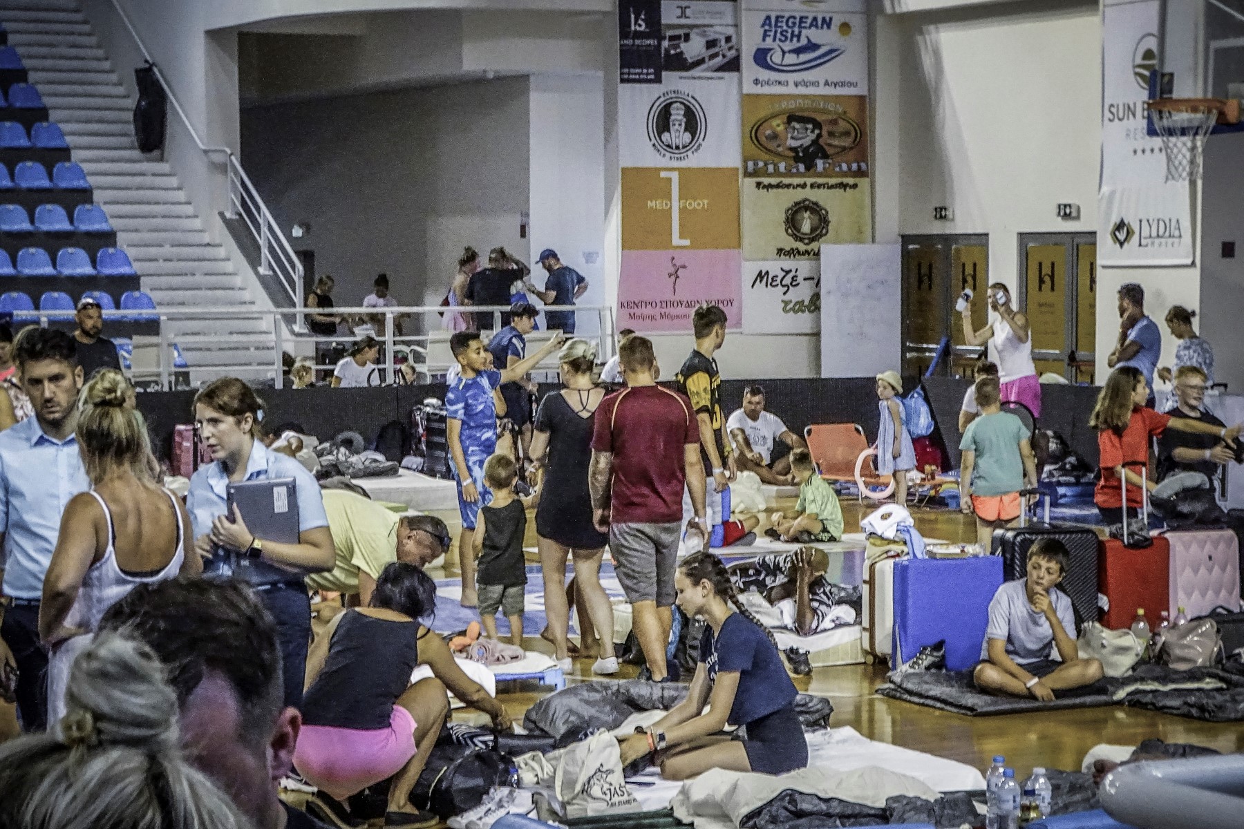 Des touristes ont passé leur nuit dans une salle de basket-ball en raison de l'incendie de forêt à Rhodes, sur l'île grecque de Rhodes, le 23 juillet 2023. (Photo par STRINGER / Eurokinissi / AFP)