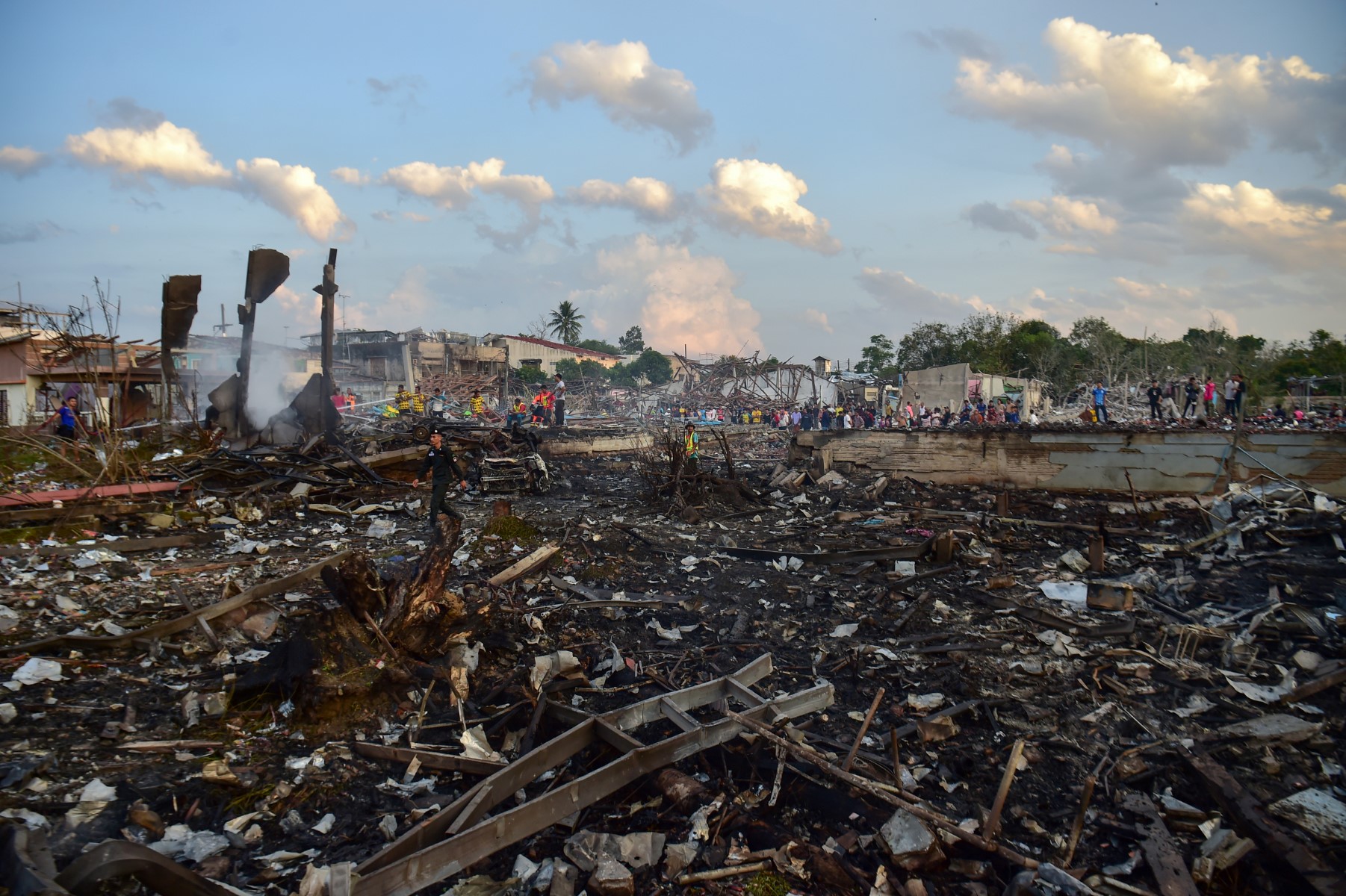 La police thaïlandaise, les équipes de secours et les habitants se rassemblent autour des maisons détruites après l'explosion d'un entrepôt de feux d'artifice, qui a fait neuf morts et plus de 100 blessés, dans le district de Sungai Kolok, dans la province de Narathiwat, dans le sud de la Thaïlande, le 29 juillet 2023. (Photo de Madaree Tohlala / AFP)