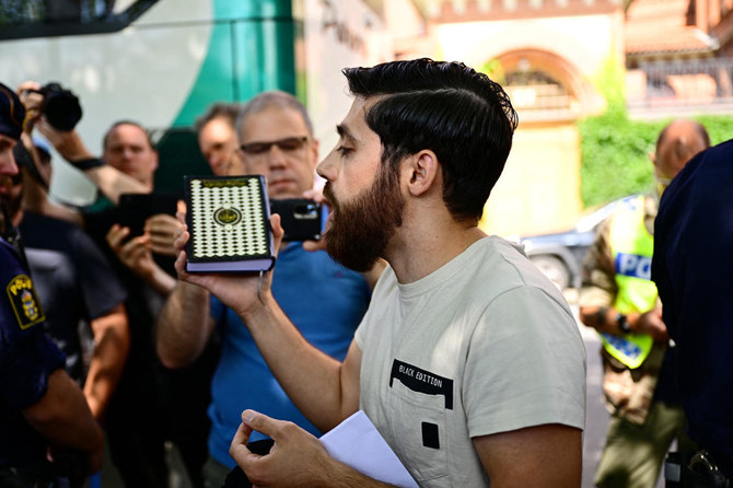 Une personne qui a reçu l'autorisation de la police de brûler une Torah et une Bible devant l'ambassade d'Israël lors d'un rassemblement public, tient un Coran dans sa main après avoir choisi de ne pas brûler les livres à Stockholm le 15 juillet 2023. (Reuters)