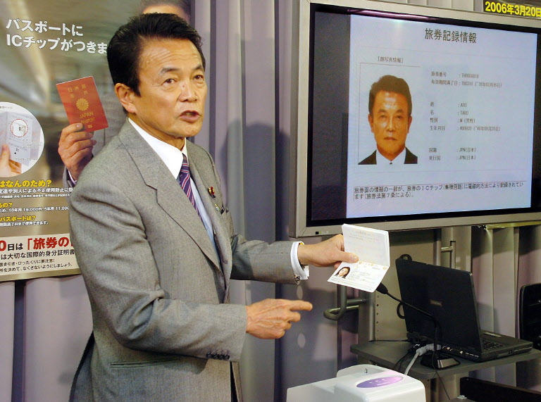 L’ancien ministre japonais des affaires étrangères, Taro Aso, fait la démonstration d'un passeport électronique contenant des informations personnelles et un portrait numérique du voyageur sur une puce électronique sans contact, afin d'éviter les faux passeports et de faciliter le contrôle des passeports au bureau de l'immigration du ministère des affaires étrangères, à Tokyo, le 17 mars 2006. (Photo JIJI PRESS / AFP)