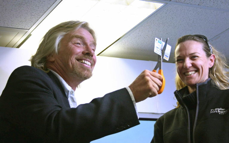 L'entrepreneur britannique Richard Branson (à gauche) coupe une carte de crédit d'une banque sud-africaine lors du lancement de la carte de crédit Virgin Money, le 26 juin 2006, à Johannesburg. (Photo by Fati Moalusi / AFP)