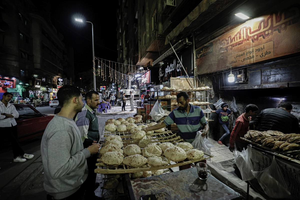 Des gens achètent des pains plats devant une boulangerie dans le centre-ville du Caire. (Photo par Khaled Desouki / AFP)