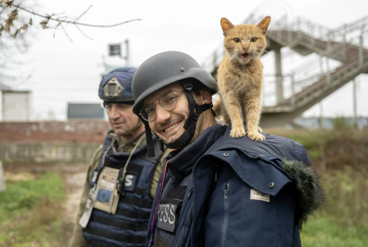 Le journaliste de l'AFP Arman Soldin sourit au photographe alors qu'un chat se tient sur ses épaules lors d'une mission pour l'AFP en Ukraine, le 11 novembre 2022. (Photo par Bulent KILIC / AFP)