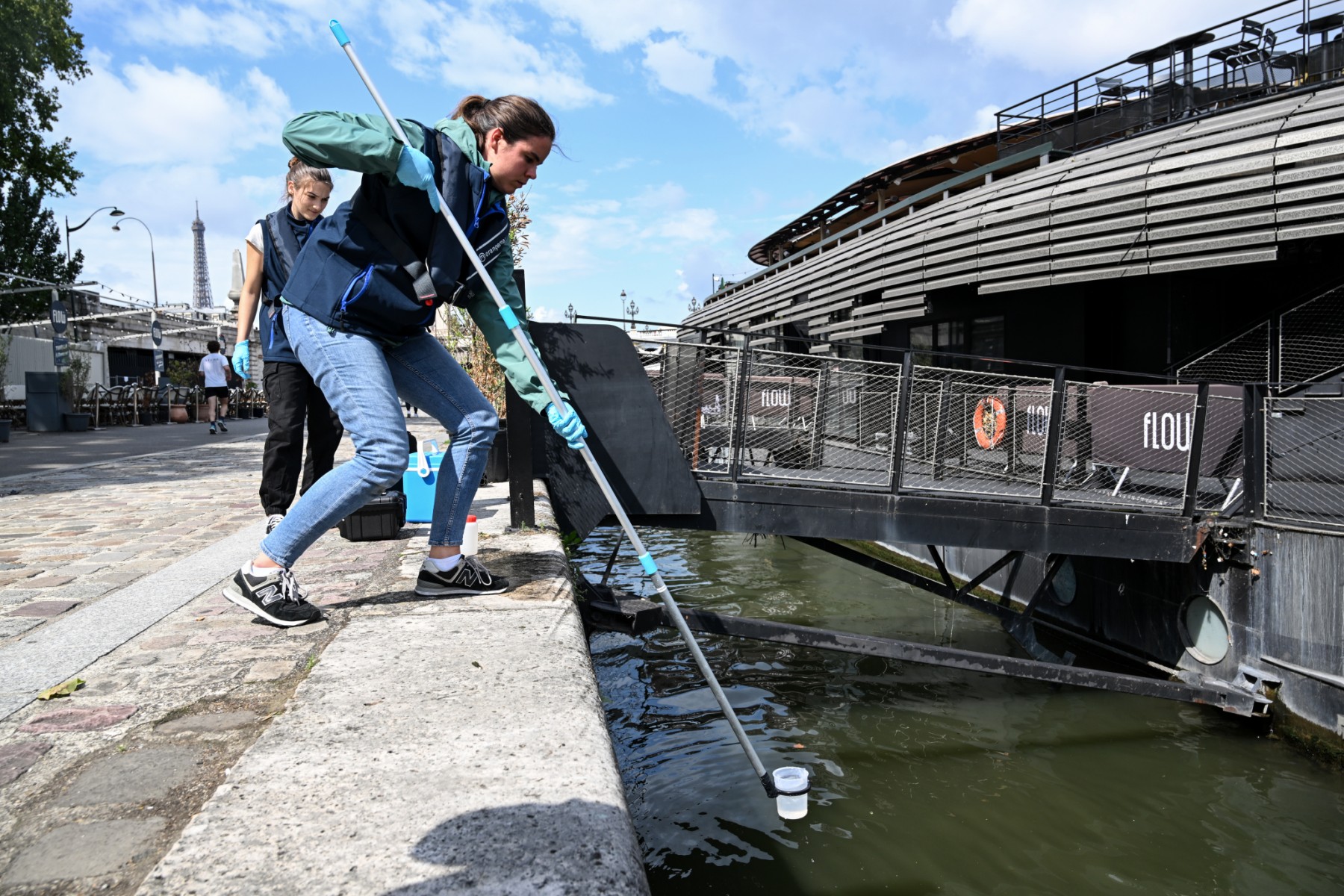 Un employé de la société Fluidion prélève un échantillon d'eau de la Seine pour en analyser la composition en vue des Jeux olympiques de Paris 2024, près du Pont Alexandre III à Paris, le 4 août 2023. (Photo par Bertrand GUAY / AFP)