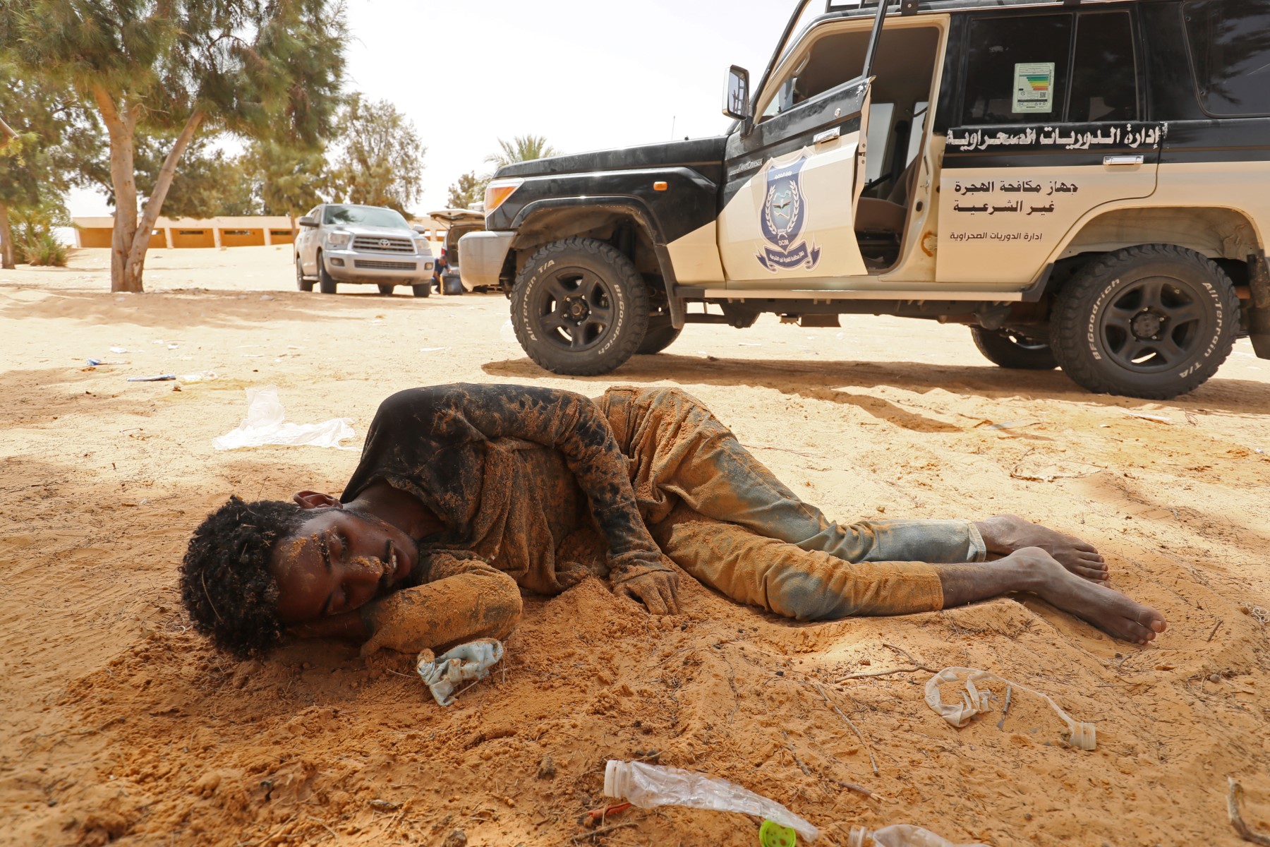 Un migrant d'origine africaine s'effondre à son arrivée dans une zone inhabitée près d'Al-Assah, à la frontière entre la Libye et la Tunisie, le 30 juillet 2023. (Photo par Mahmud Turkia / AFP)