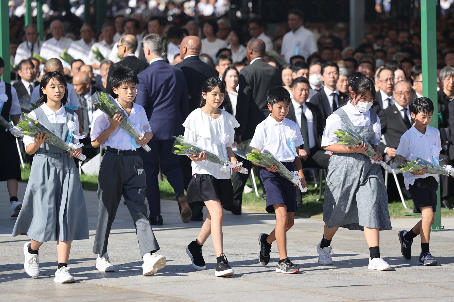 Des écoliers se préparent à déposer des fleurs lors d'une cérémonie marquant le 78e anniversaire de la première attaque atomique au monde, au Parc commémoratif de la paix à Hiroshima, le 6 août 2023. (Photo par JIJI PRESS / AFP)