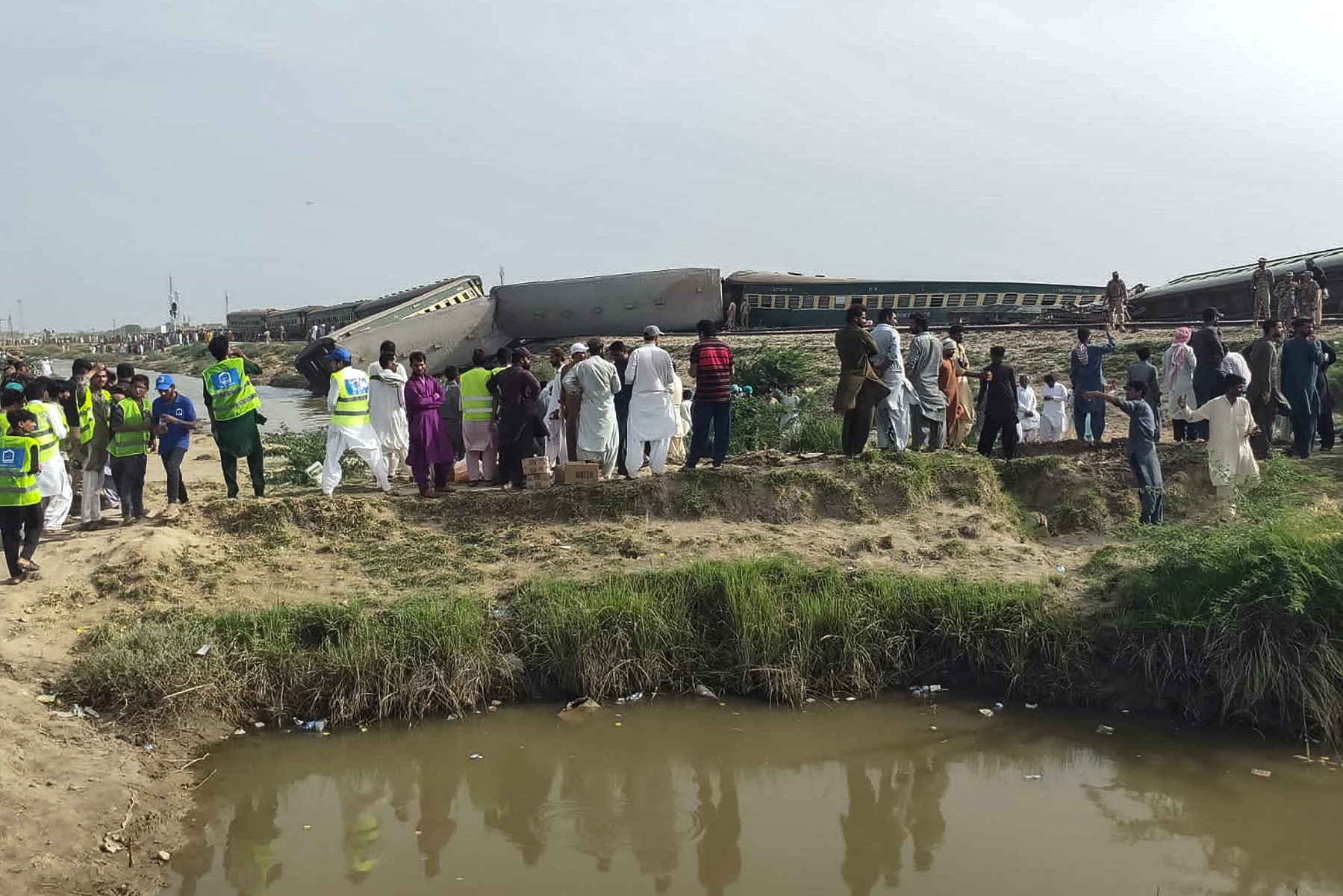 Des habitants et des bénévoles se rassemblent près des wagons sur le site de l'accident après le déraillement d'un train de passagers à Nawabshah, dans la province méridionale de Sindh au Pakistan, le 6 août 2023. (Photo par AFP)