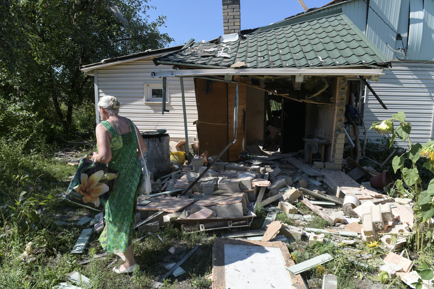 Lyubov Tolchina, 63 ans, marche dans le jardin jonché de décombres de la maison de son fils, tué lors des bombardements ukrainiens sur Donetsk, la capitale de l'État autoproclamé de la République populaire de Donetsk (RPD), dans l'est de l'Ukraine, le 13 août 2023. (AFP).