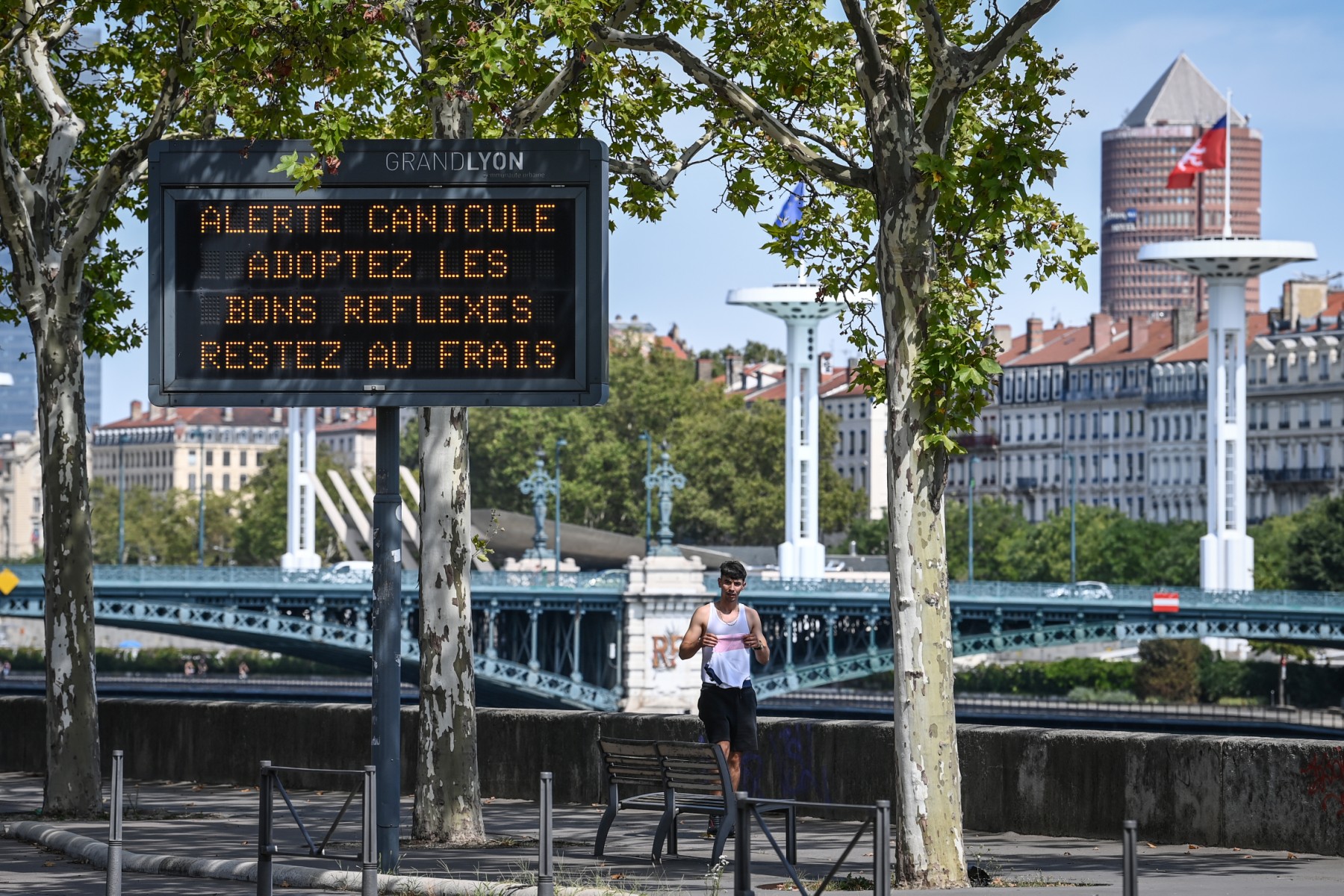 Un coureur passe devant un panneau indiquant la canicule à Lyon, le 18 août 2023. (Photo Olivier Chassignole / AFP)