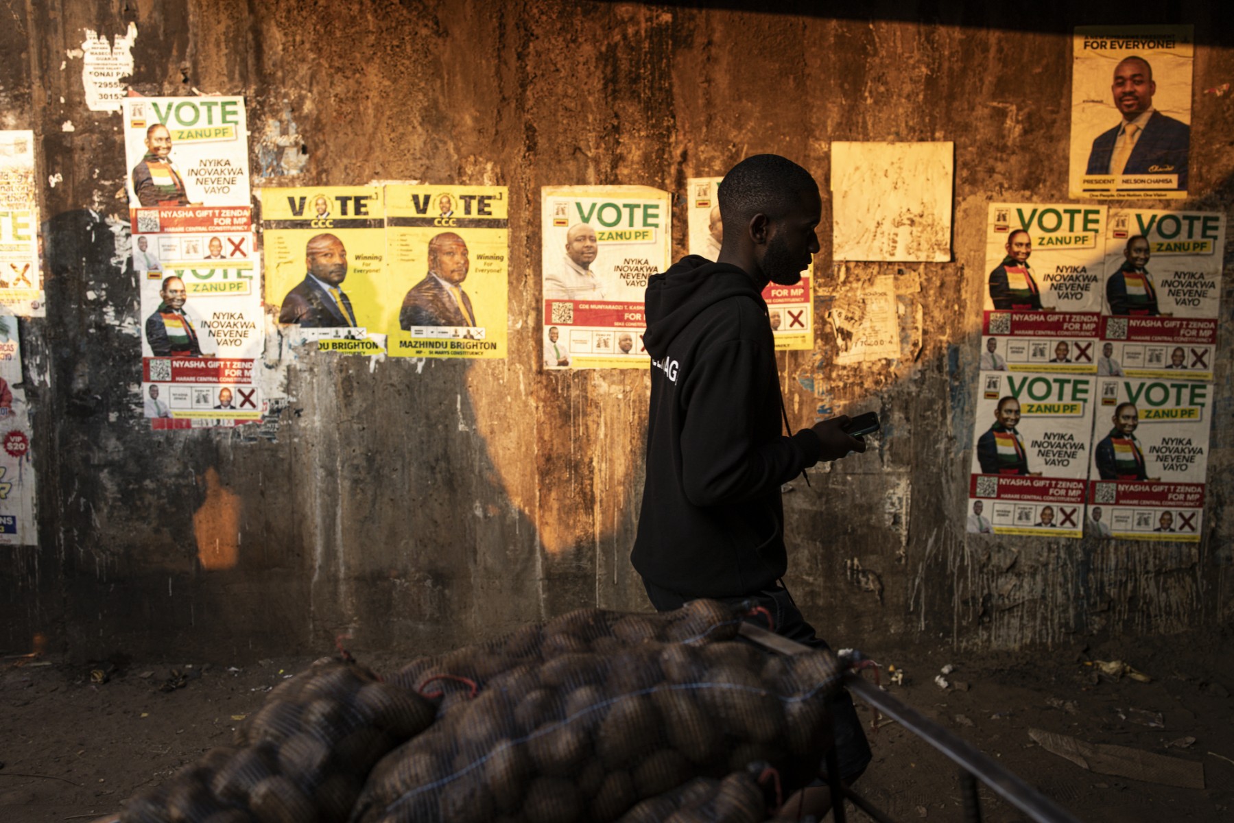Un homme passe devant des affiches de campagne à Harare le 19 août 2023. Les Zimbabwéens se rendront aux urnes le 23 août 2023 pour les élections générales et présidentielles. (Photo par John Wessels / AFP)