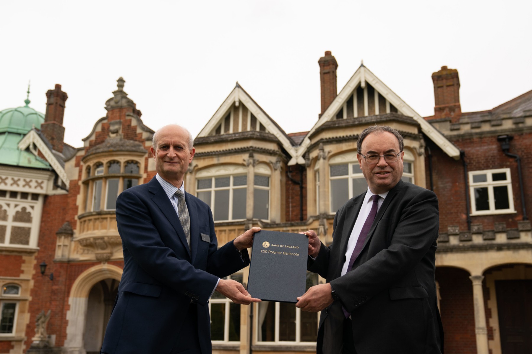 Le gouverneur de la Banque d'Angleterre Andrew Bailey (à droite) présente au directeur général de Bletchley Park Iain Standen un nouveau billet de cinquante livres sterling (GBP), représentant le mathématicien et scientifique Alan Turing, à Bletchley Park à Milton Keynes, le 21 juin 2021. (Joe Giddens/ Pool/AFP) /