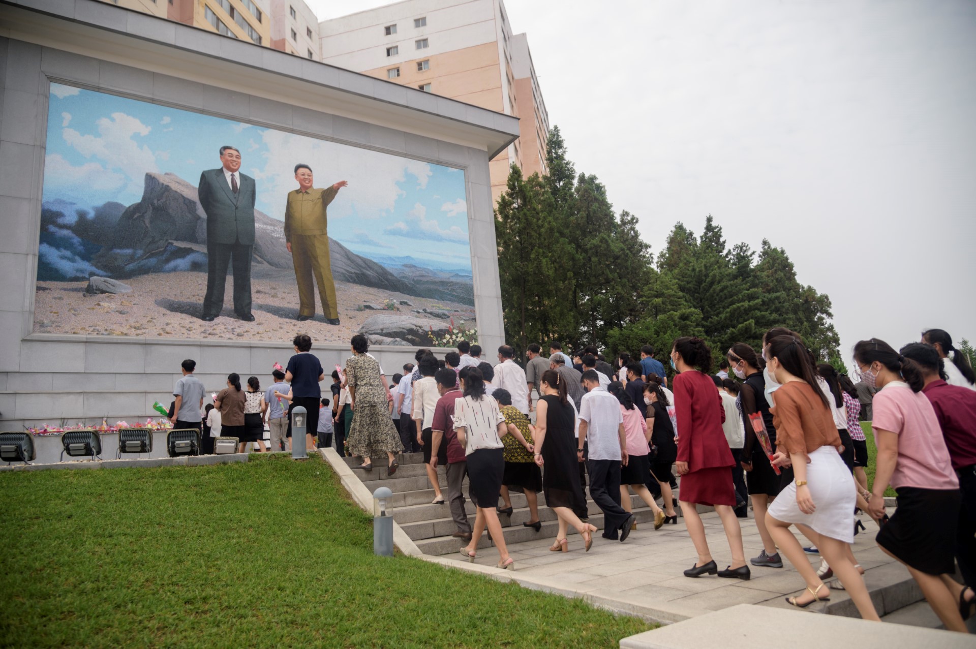 Des personnes visitent un portrait en mosaïque des dirigeants nord-coréens Kim Il Sung et Kim Jong Il au carrefour Dongmun dans le district de Daedonggang à Pyongyang, dans le cadre des événements marquant le 27e anniversaire de la mort de Kim Il Sung, le 8 juillet 2021. / AFP / KIM Won Jin