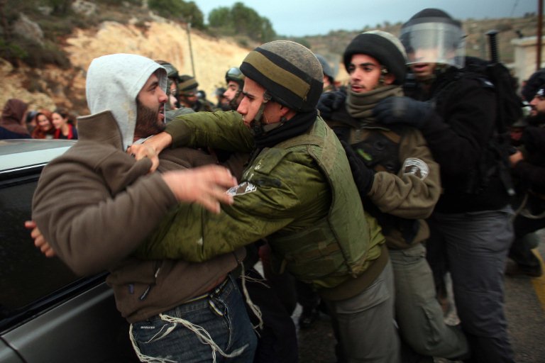 Des policiers israéliens se battent avec des colons juifs qui ont tenté de bloquer une route pour empêcher l'entrée des inspecteurs du gouvernement qui ont ordonné l'arrêt de la construction dans la colonie de Maale Levona, dans le centre de la Cisjordanie, le 7 décembre 2009. (Photo by Daniel Bar-On / AFP)