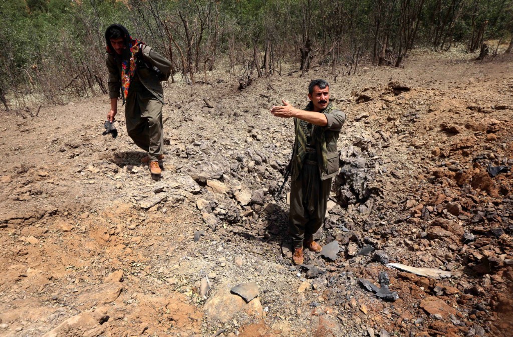 Des membres du Parti des travailleurs du Kurdistan (PKK) inspectent un cratère qui aurait été causé par une frappe aérienne des avions de guerre turcs le 29 juillet 2015 dans la montagne Qandil, le quartier général du PKK dans le nord de l'Irak. (Photo de Safin HAMID / AFP)