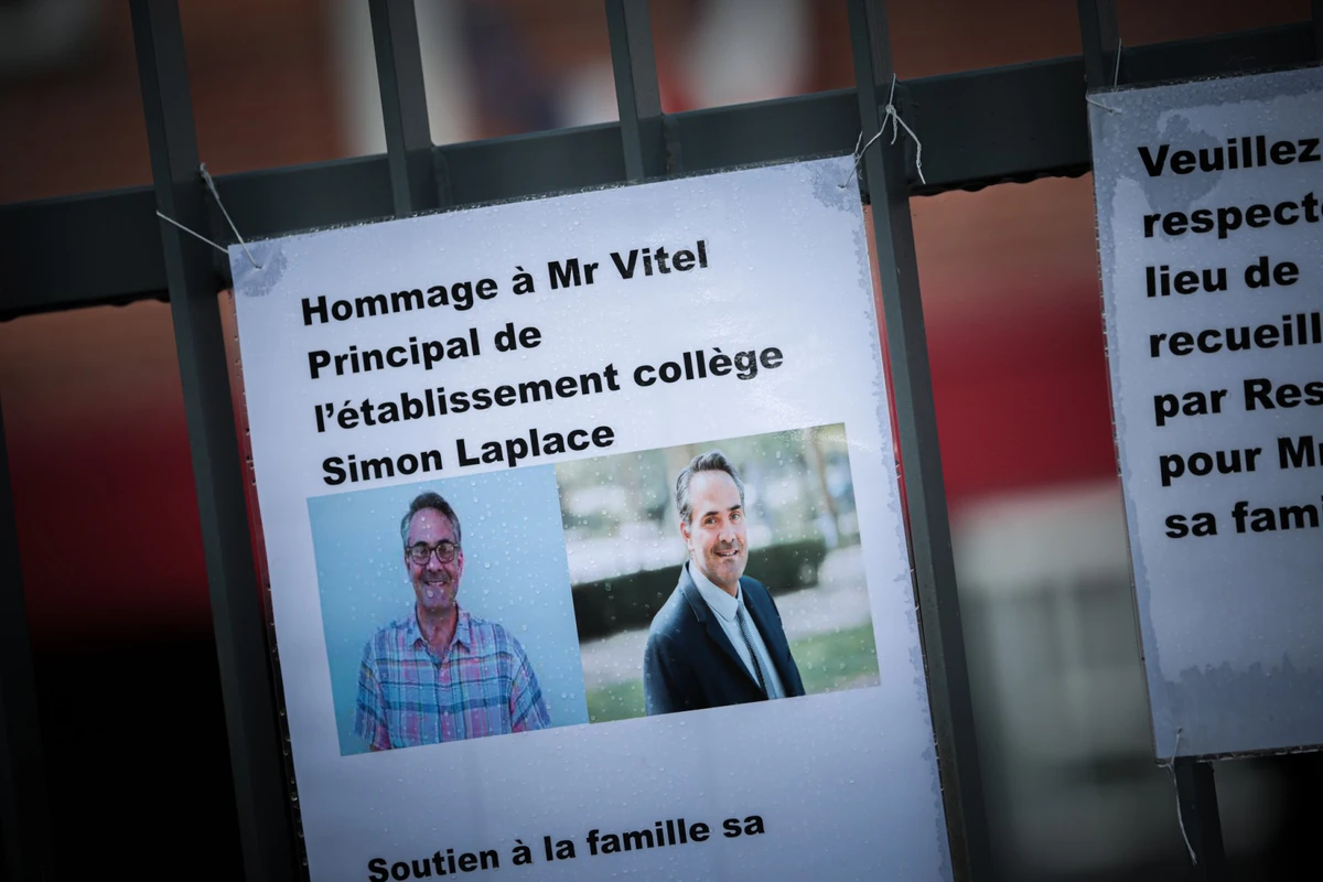 Des pancartes avec le portrait du principal du collège Pierre Simon De Laplace sont affichées sur les grilles de l'école de Lisieux, dans le nord-ouest de la France, le 12 août 2023, après qu'il a été retrouvé mort dans des circonstances suspectes le 11 août 2023 au matin dans son école. (Photo Lou Benoist / AFP)