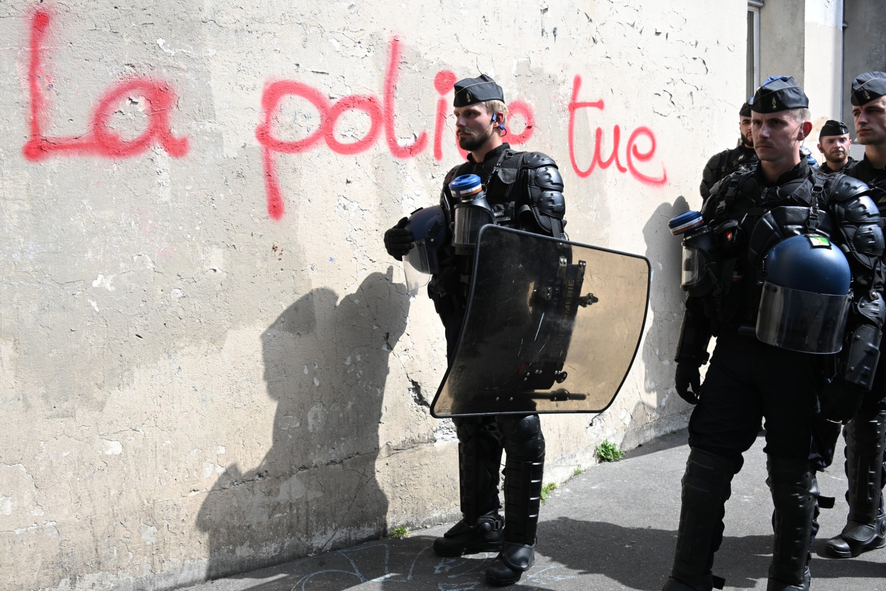 Des gendarmes mobiles montent la garde à côté d'un graffiti indiquant "la police tue" lors de la "Marche pour Adama Traore" - sept ans après sa mort - à la Gare de l'Est à Paris le 8 juillet 2023. (Photo par Bertrand Guay AFP)