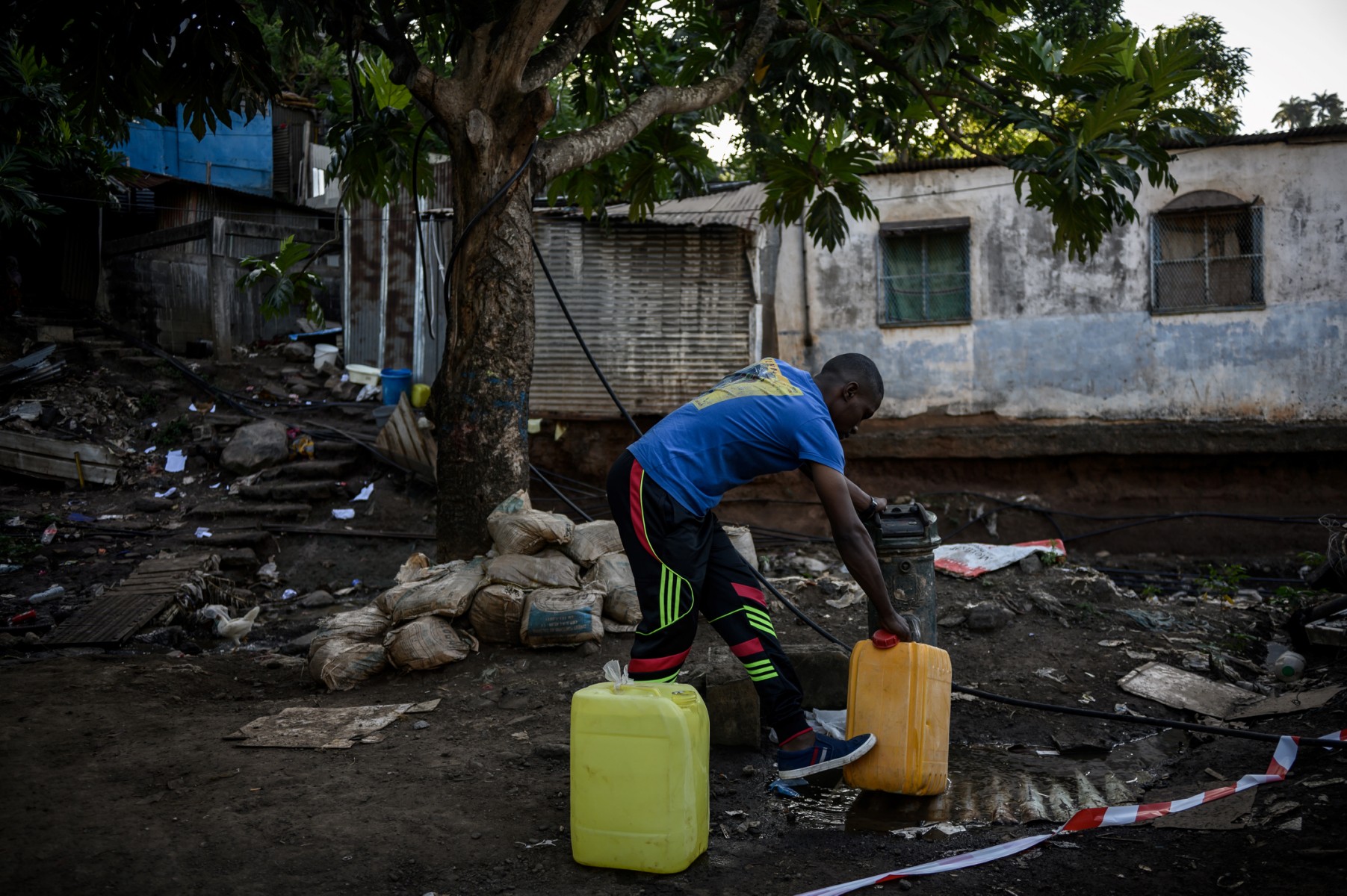 Une photo prise le 23 mai 2023 à Koungou montre un habitant remplissant des bidons d'eau potable près du bidonville du quartier "Talus 2" à Koungou sur l'île française de Mayotte dans l'océan Indien. (Photo Philippe Lopez / AFP)