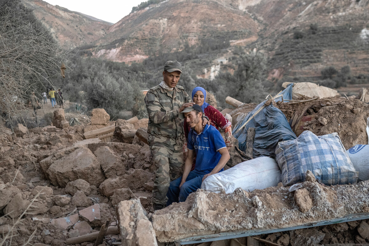 Un soldat marocain réconforte un homme assis sur les décombres dans la région montagneuse de Tizi N Test, dans la province de Taroudant, l'une des plus dévastées du Maroc frappé par le séisme, le 11 septembre 2023. (Photo BULENT KILIC / AFP)