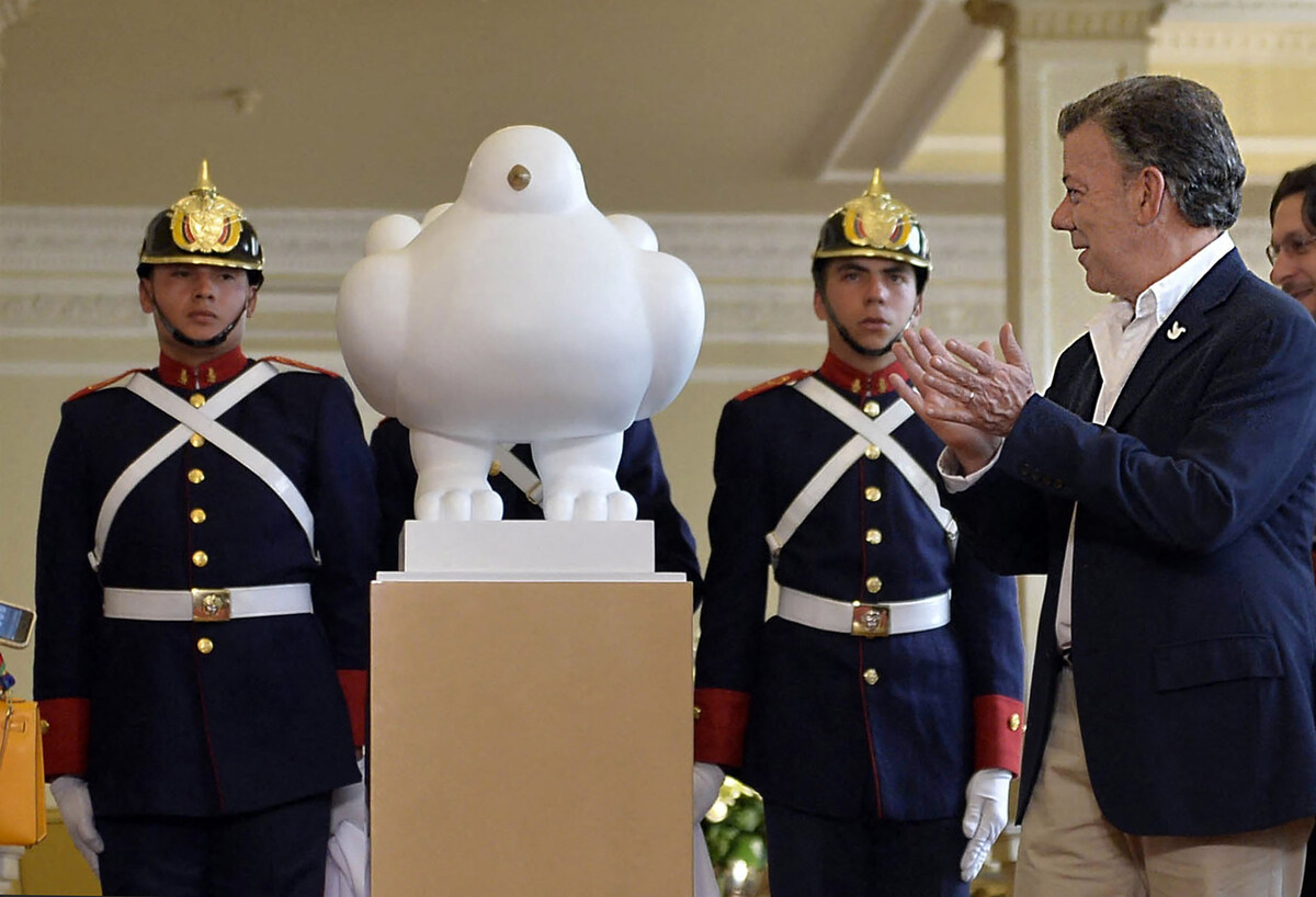 Photo diffusée par la présidence colombienne montrant le président colombien Juan Manuel Santos (à droite) applaudissant après avoir reçu la sculpture "La colombe de la paix", un cadeau de l'artiste colombien Fernando Botero, au palais présidentiel de Narino à Bogota, le 24 septembre 2016. (Photo Juan David Tena / Présidence colombienne / AFP)